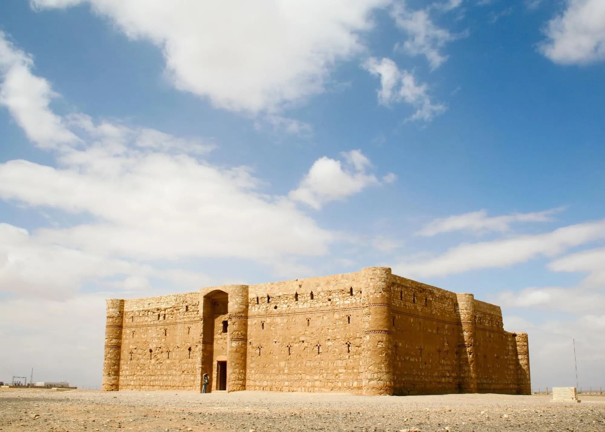 Well-preserved Qasr al-Kharanah desert castle in Jordan with visitor at entrance showing monument accessibility