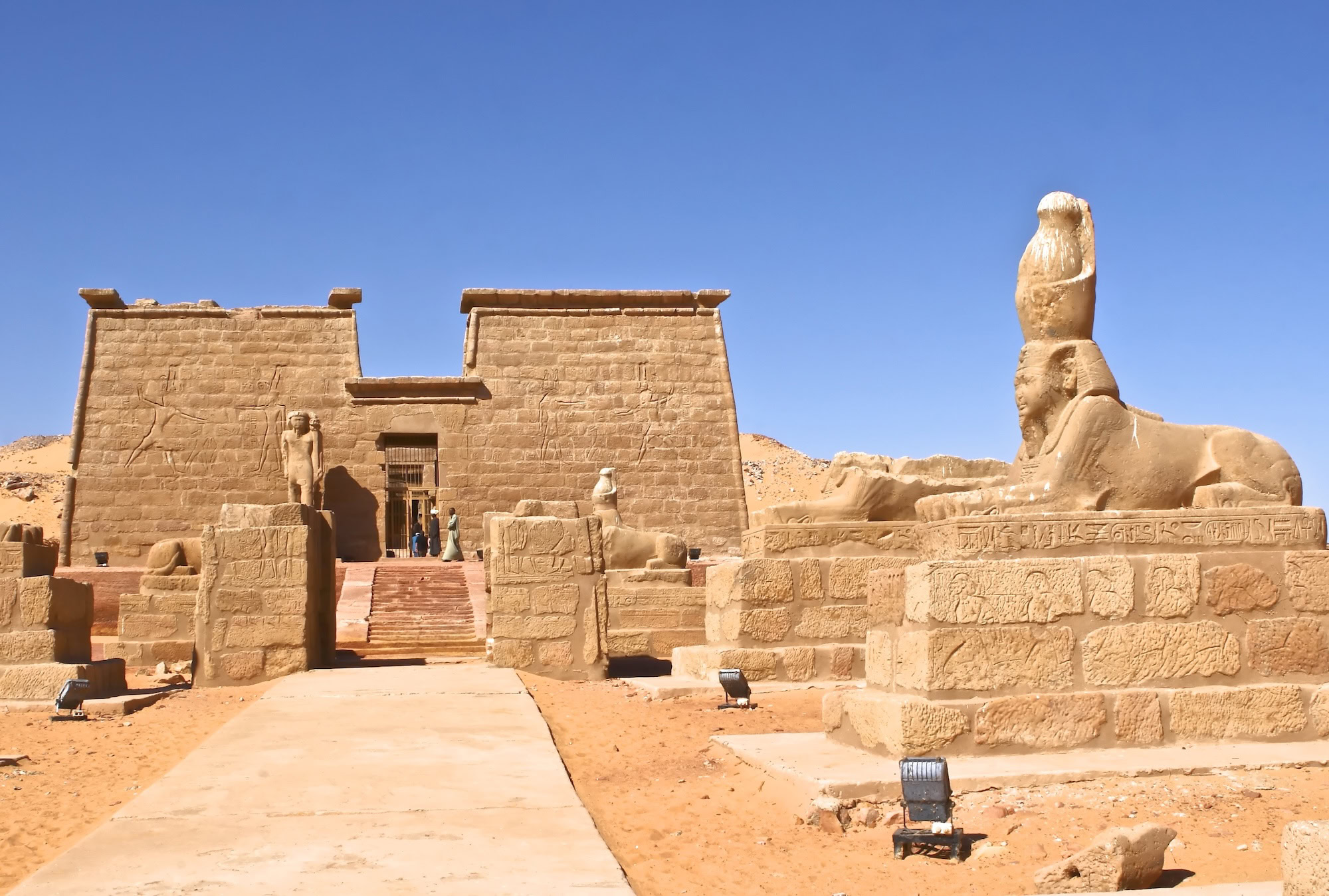 Turistas visitando templo egipcio antiguo con esfinge y jeroglíficos