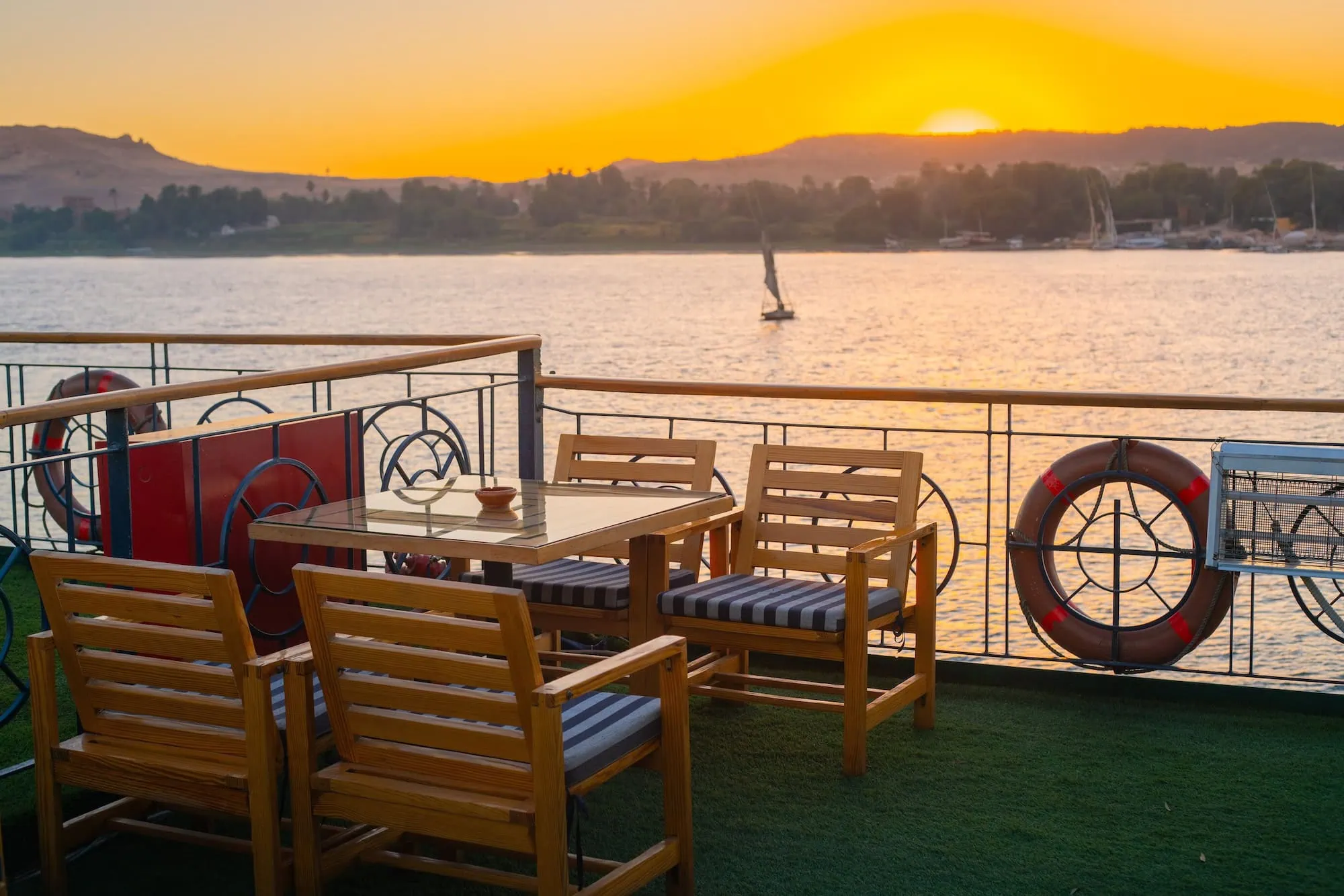 Sunset view from Nile cruise ship deck with dining furniture overlooking the River Nile in Aswan