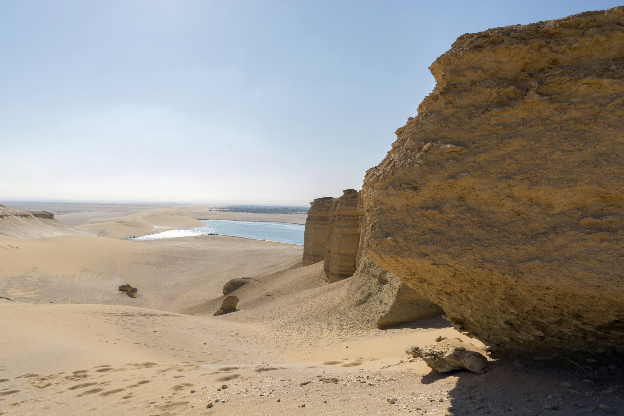 Desert landscape with sandy terrain and rock formations at Wadi El Rayan