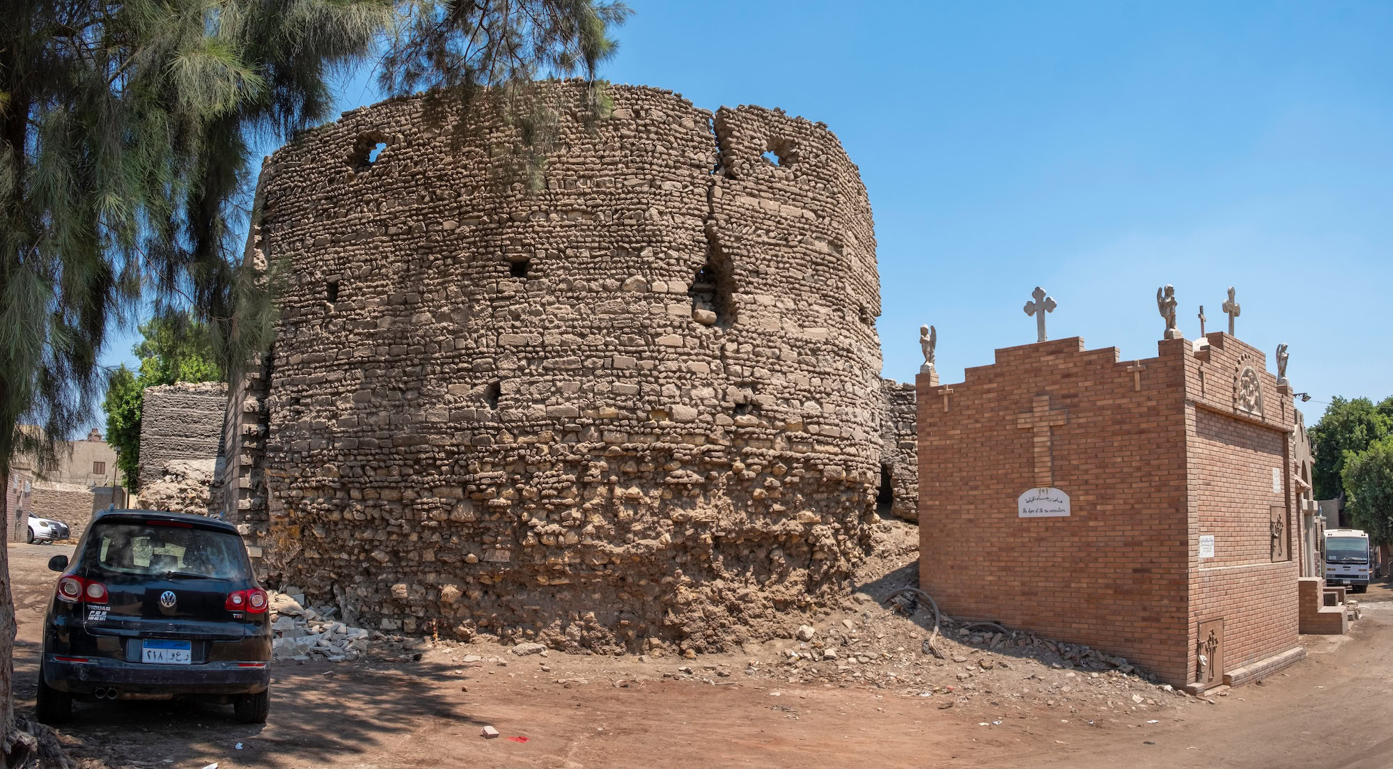 Ancient Roman Babylon Fortress ruins with circular stone tower and modern Coptic church in Cairo