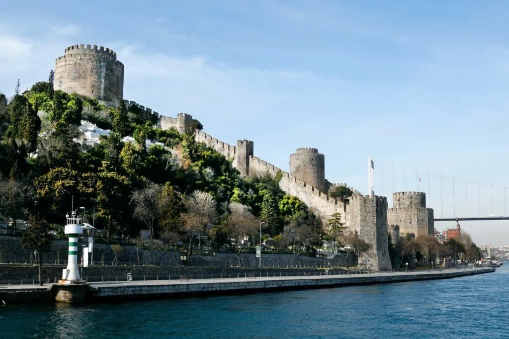 Rumeli Fortress seen from the Bosphorus shoreline with stone towers and walls rising above the water in Istanbul