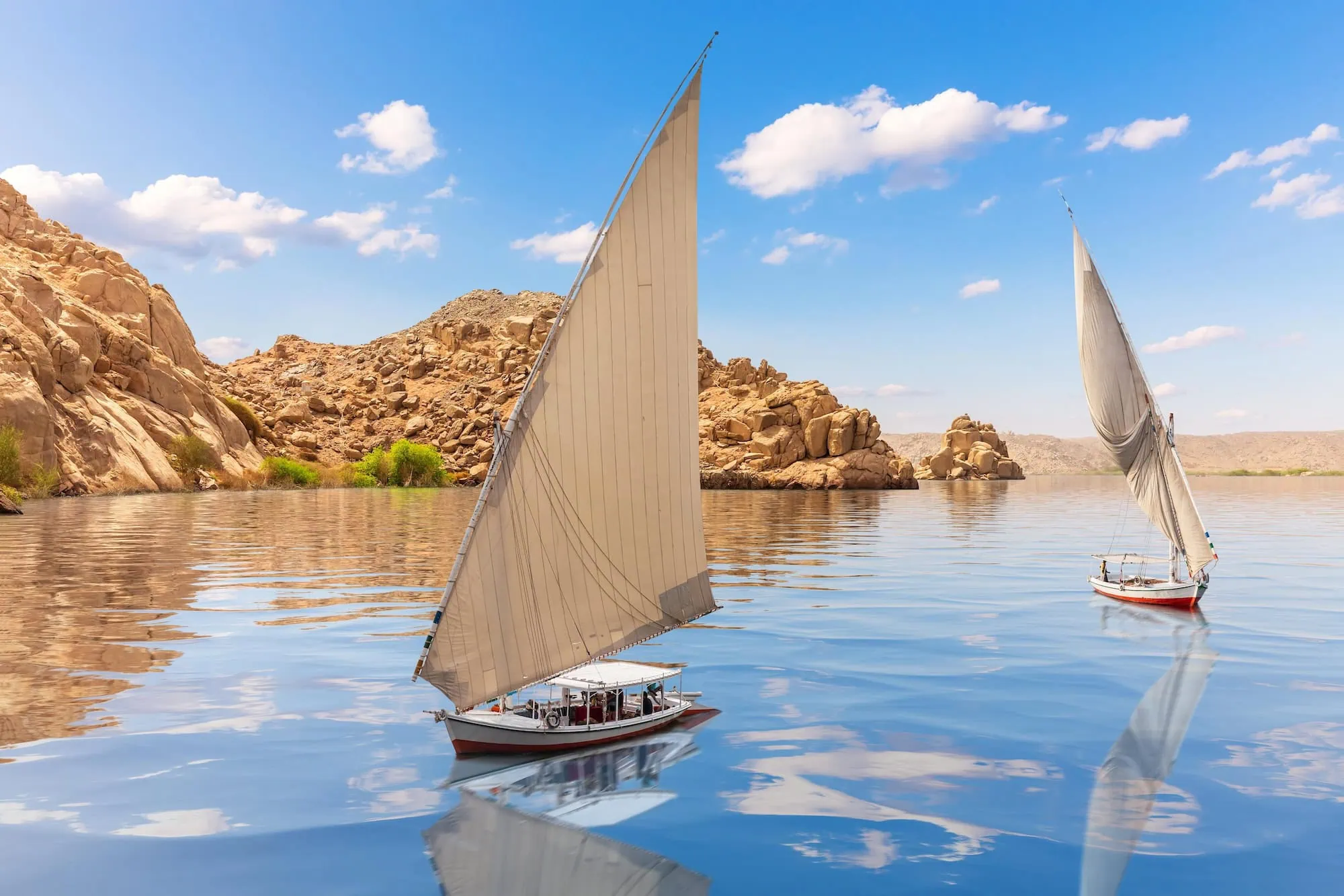 Traditional Egyptian feluccas with white sails sailing peacefully on the Nile River