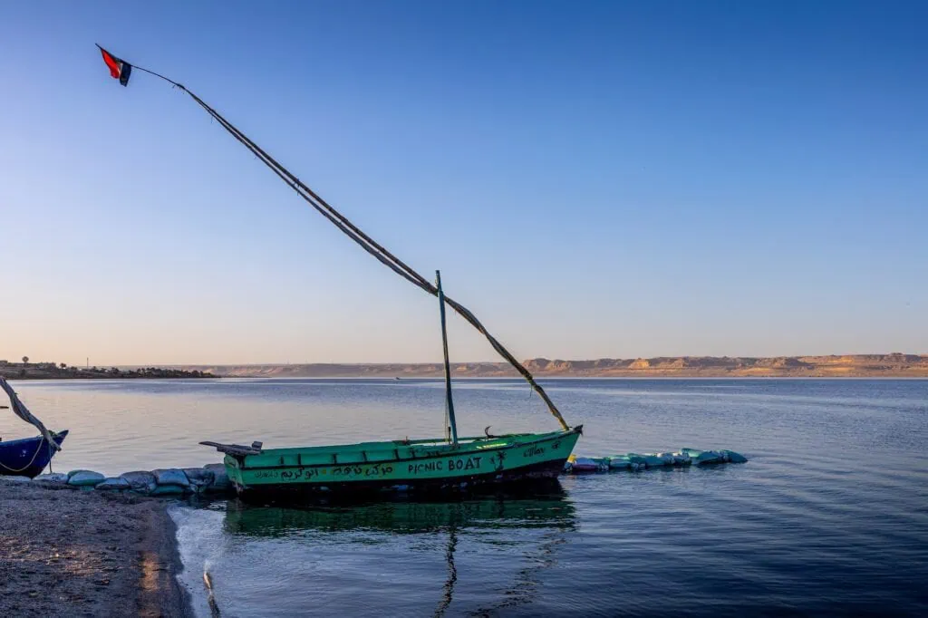 Sailing boat silhouetted against the sunset on Lake Moeris with calm water and distant shoreline, Fayoum