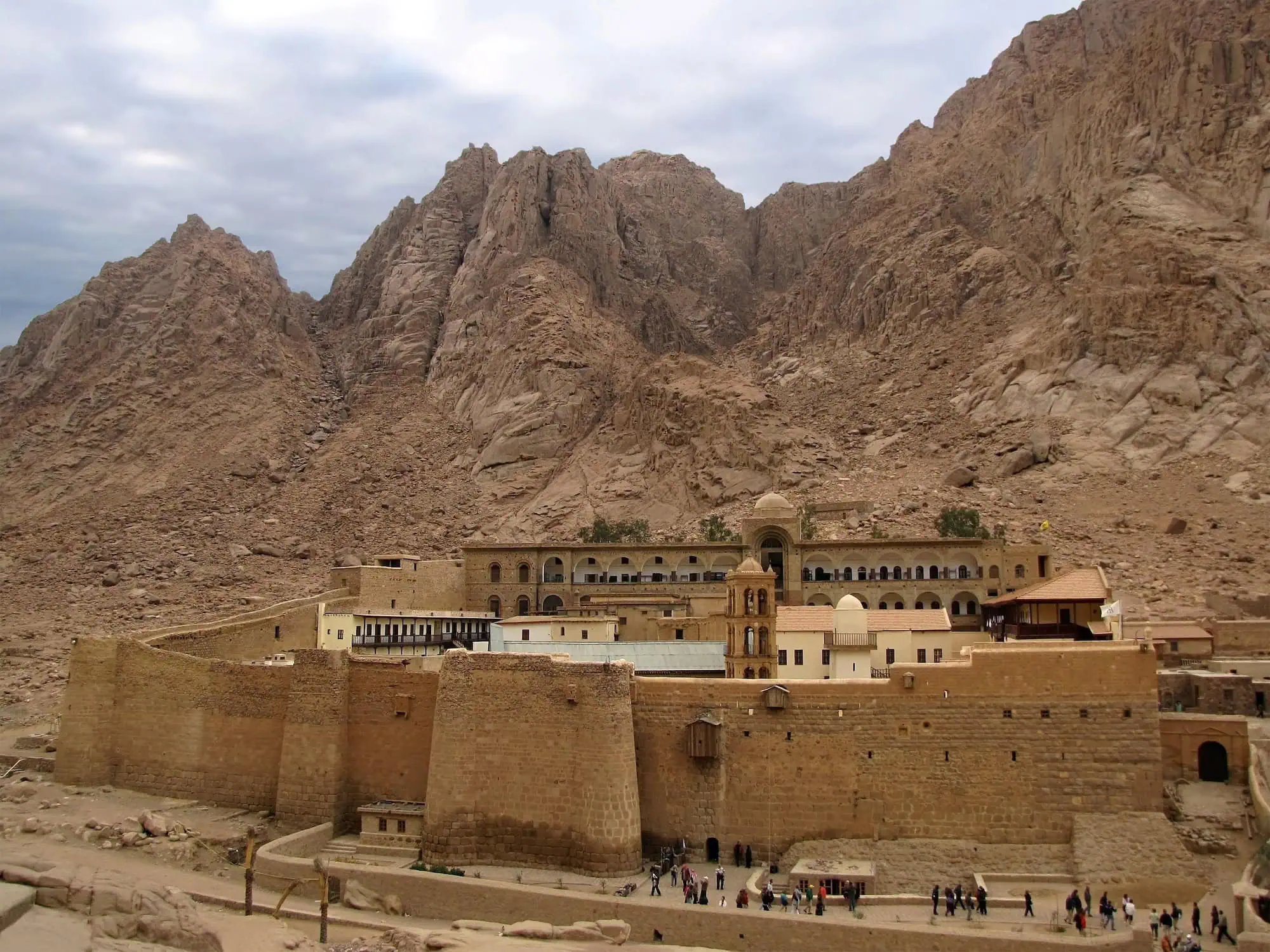 Saint Catherine's Monastery in Egypt's desert with tourists exploring the ancient fortress walls
