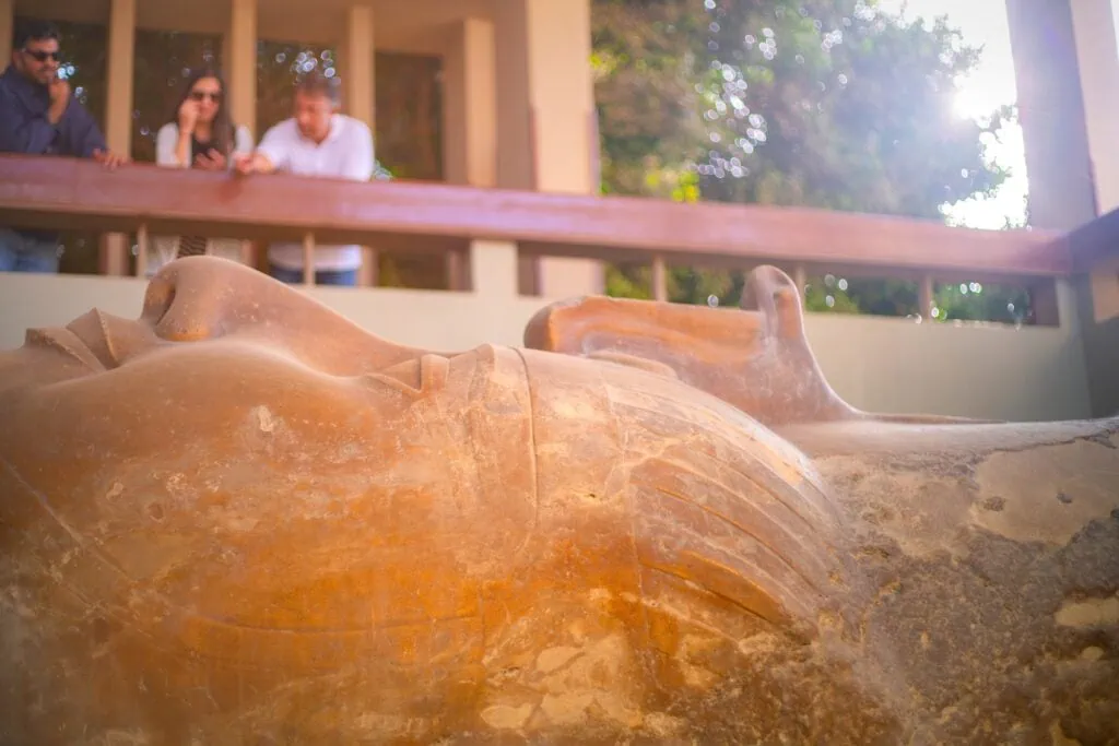 The colossal limestone statue of King Ramses II lying on its side within the open-air displays at the Mit Rahina Museum, Memphis