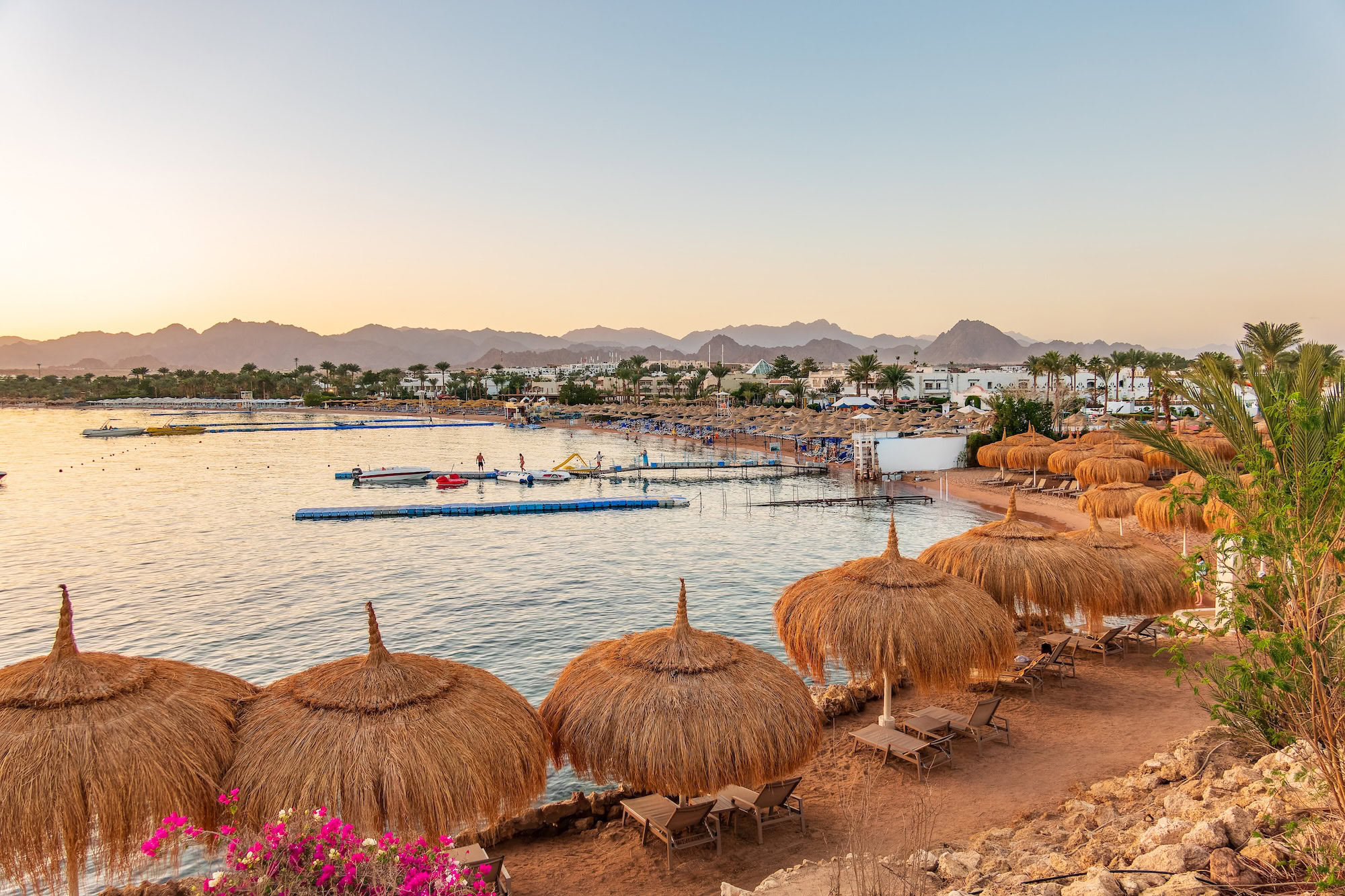 Luxury Red Sea beach resort with palm trees, umbrellas, and mountain backdrop