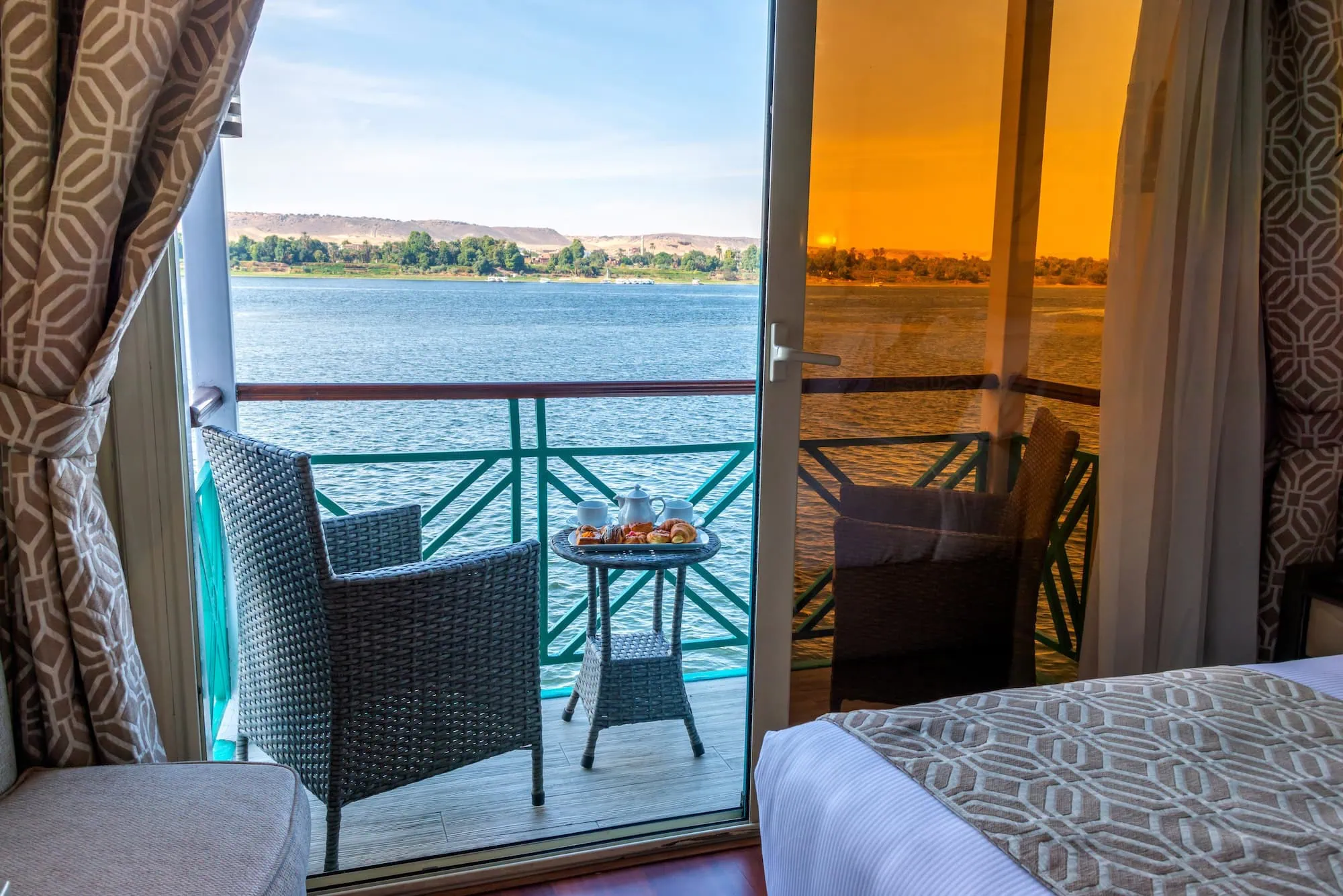 Luxury Nile River cabin interior with private balcony and panoramic windows showing desert landscape view