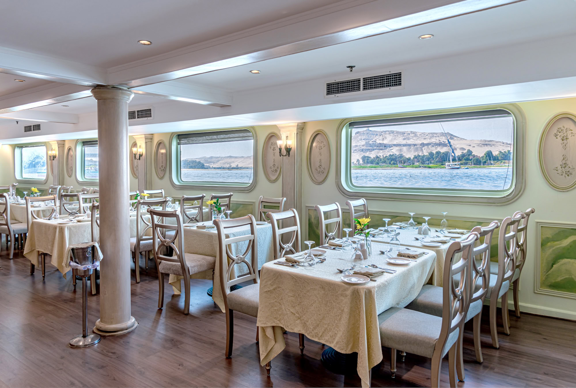 Elegante sala de jantar a bordo de um navio de cruzeiro no Rio Nilo com mesas postas e vista para o rio