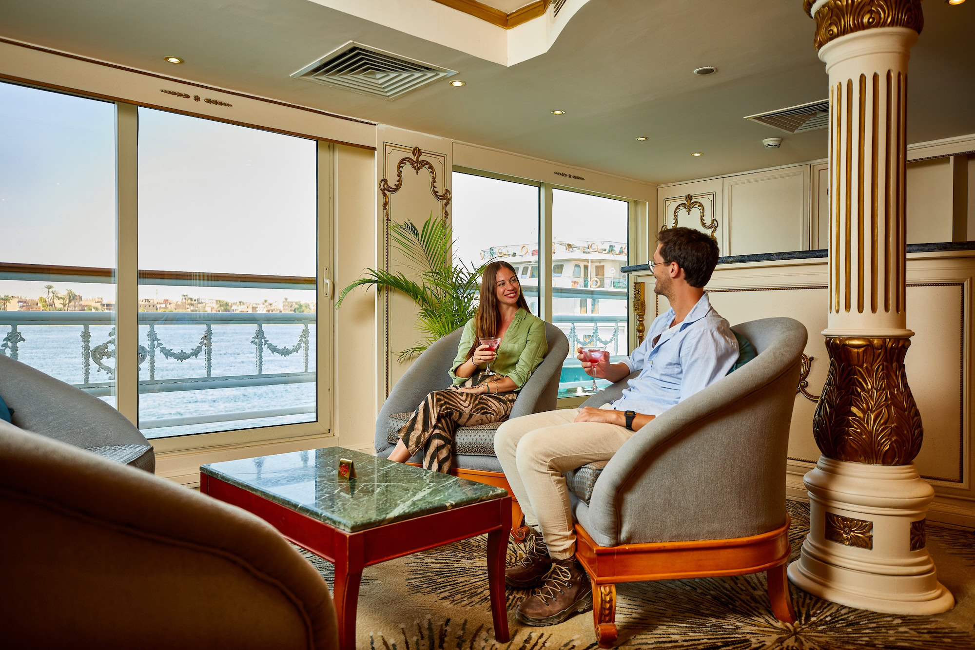 Elegant luxury river cruise ship interior with ornate columns, leather chairs, and cocktail service