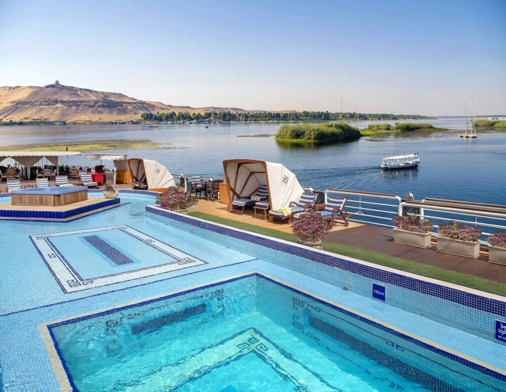 ool deck aboard the Sonesta St. George, a 5-star Luxury Nile Cruise vessel sailing the Luxor–Aswan stretch, showing the swimming pool and shaded sun-deck areas that allow comfortable on-board hours during shoulder-season and warmer-month sailings.