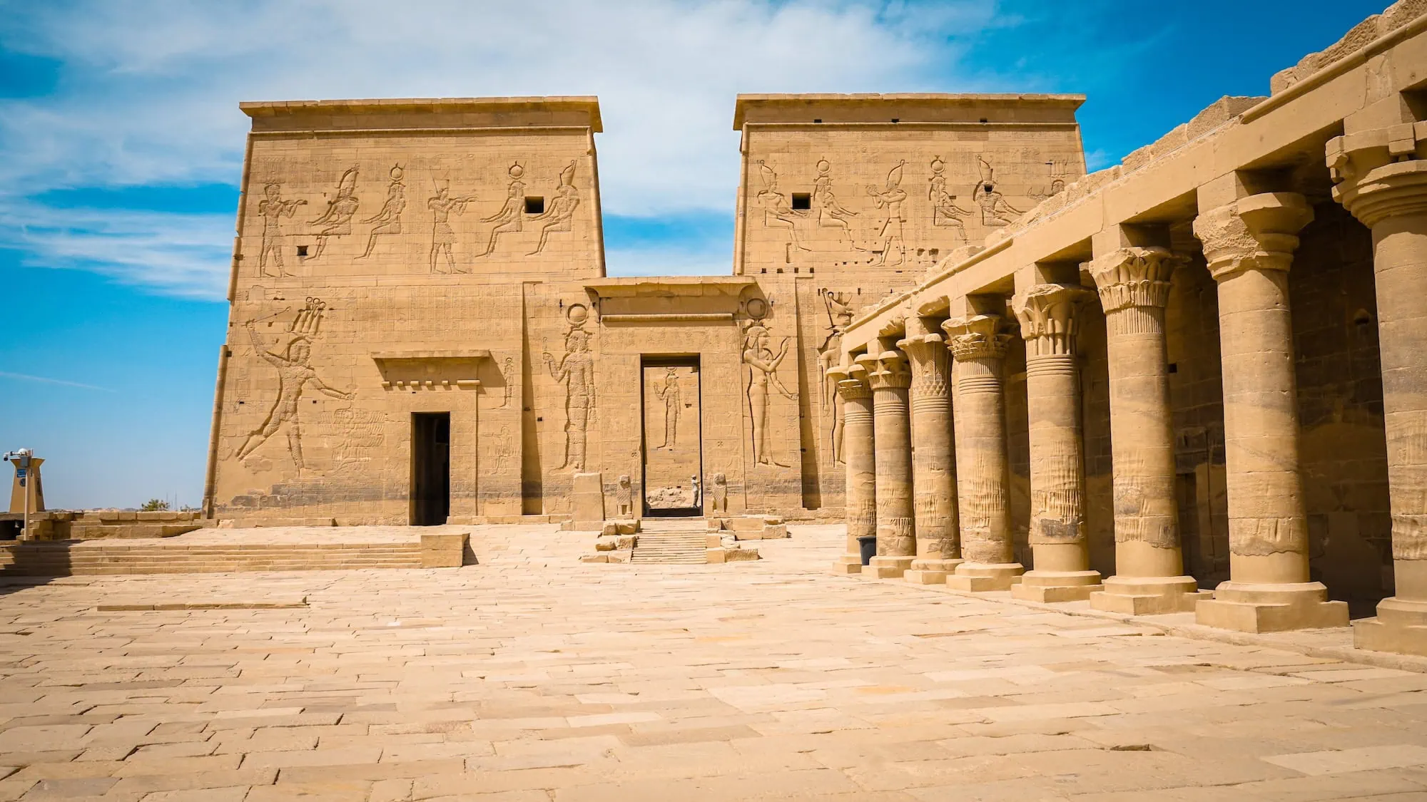 Ancient Philae Temple in Aswan showing massive sandstone pylons decorated with hieroglyphs and papyrus-topped columns