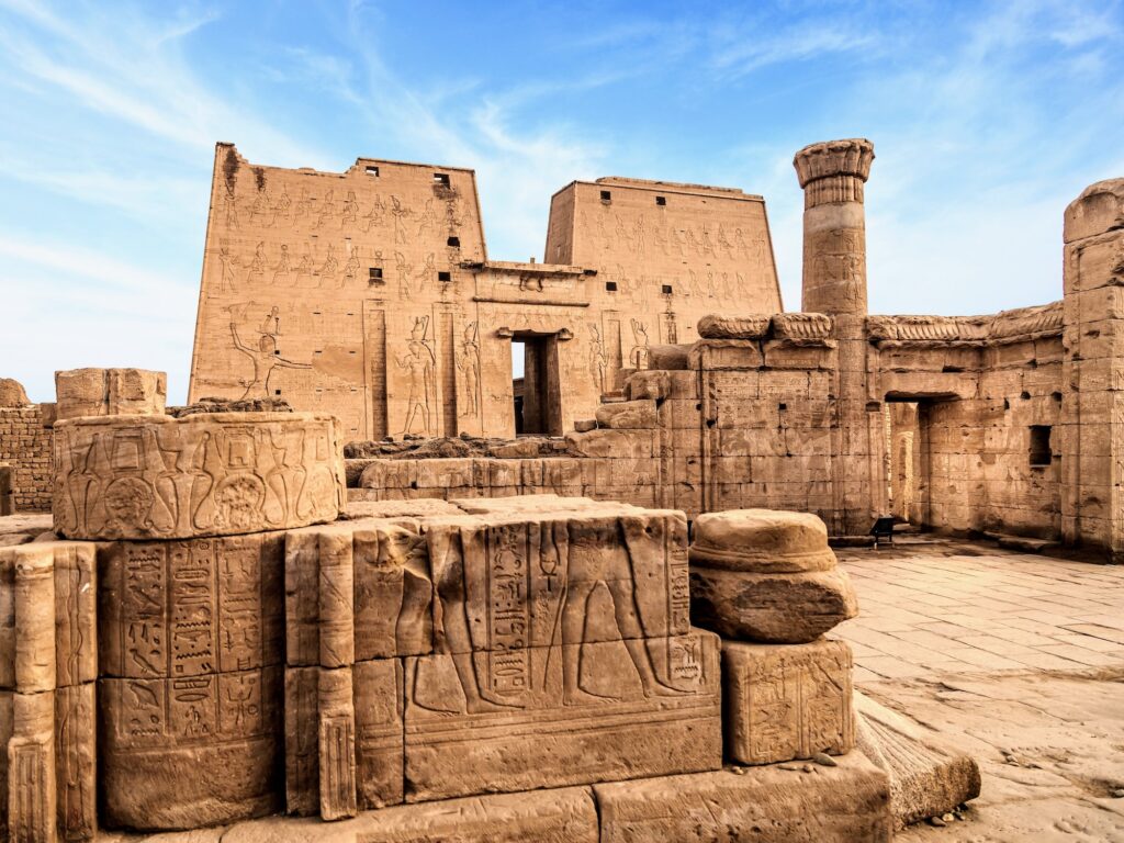Temple of Horus with monumental pylon entrance and stone walls covered in carved reliefs, Edfu