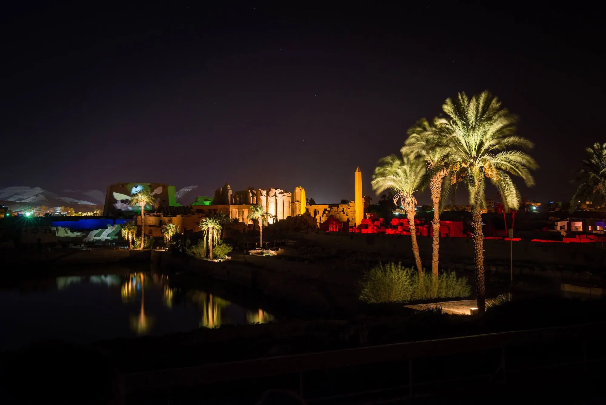 Templo de Luxor iluminado con reflejos mágicos en el agua y palmeras