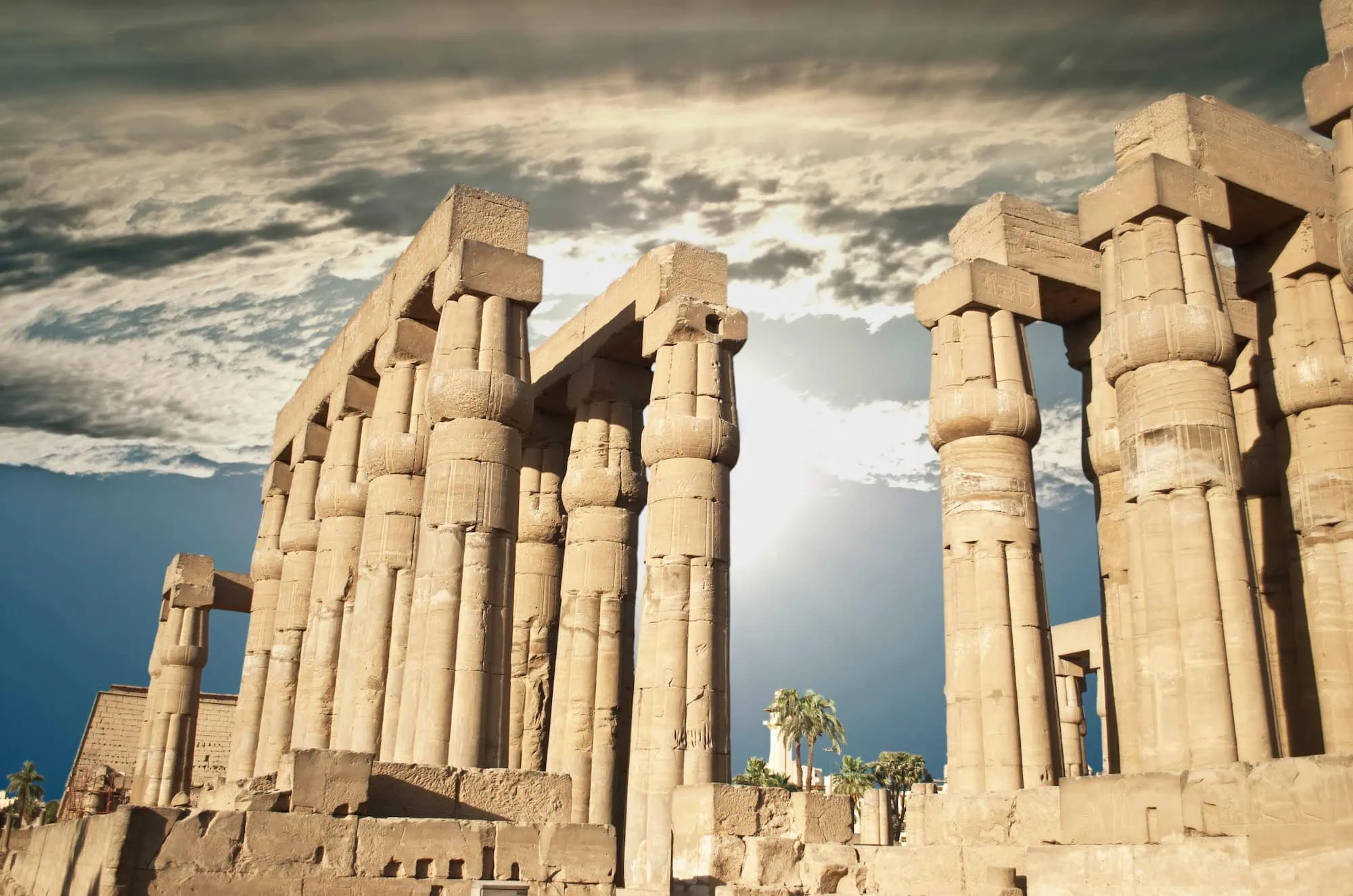 Ancient Egyptian Temple of Luxor showing massive stone columns with hieroglyphic carvings under cloudy sky - Luxor Travel Guide