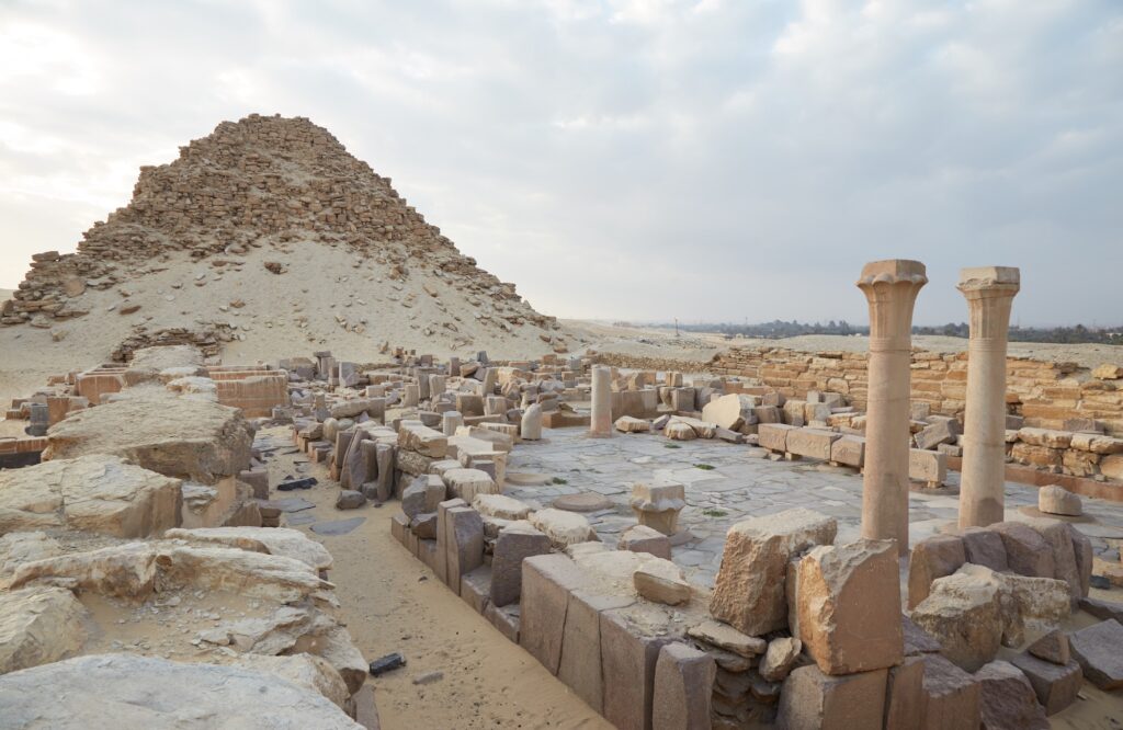Temple ruins with standing columns and a collapsed pyramid at the Abusir Pyramids Complex, Cairo