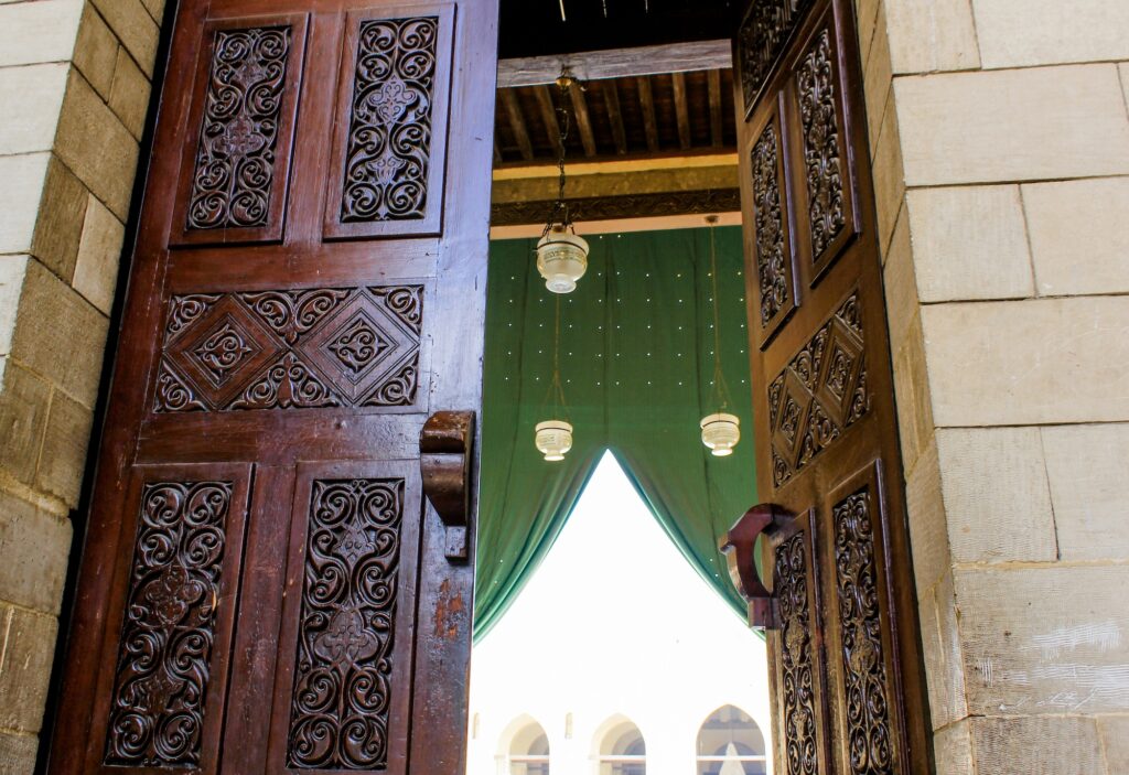An open wooden door with geometric carved patterns at the Al-Hakim bi-Amr Allah Mosque, Cairo