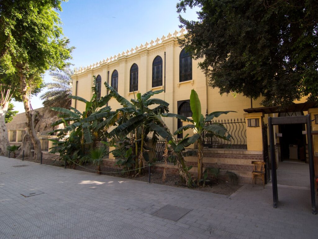 An exterior view with stone walls, arched windows, and decorative details at the Ben Ezra Synagogue, Cairo