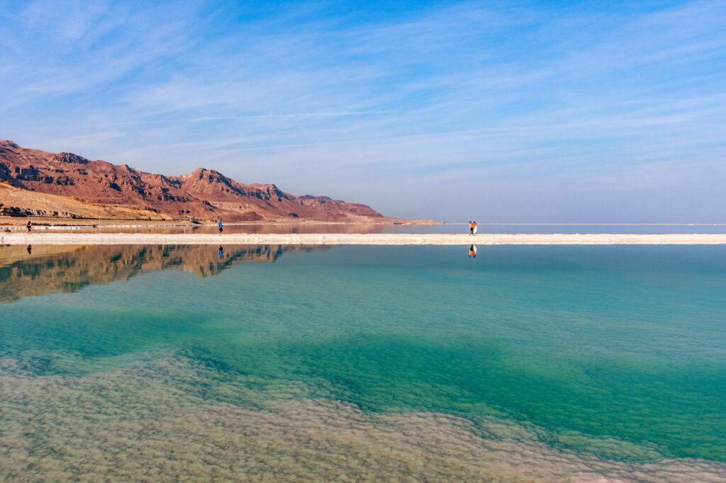 View of the Dead Sea salt lake with calm water surface, mineral-rich shoreline, and surrounding desert landscape, Ein Bokek