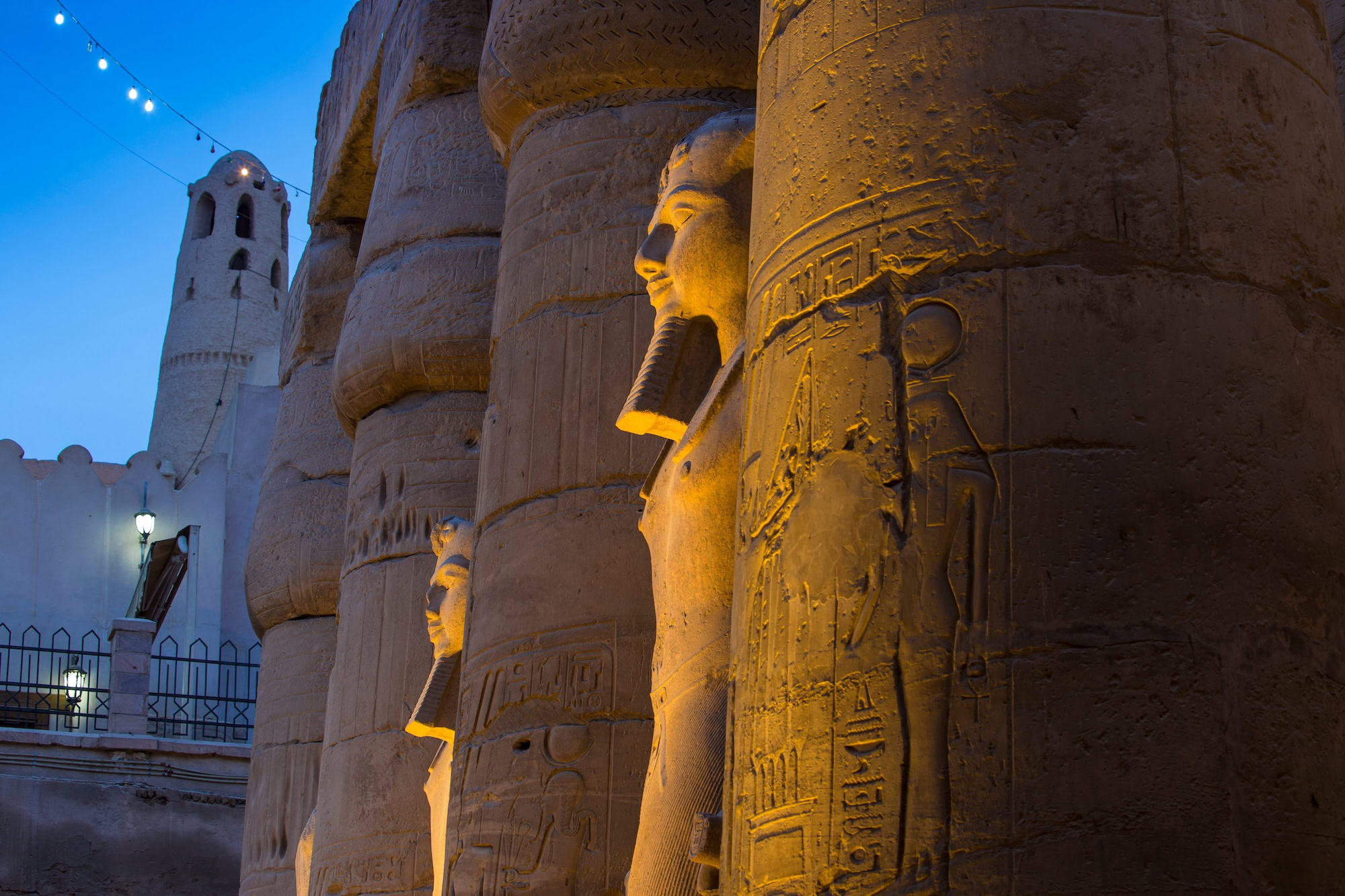Tempio di Luxor illuminato al tramonto con statue faraoniche e atmosfera magica
