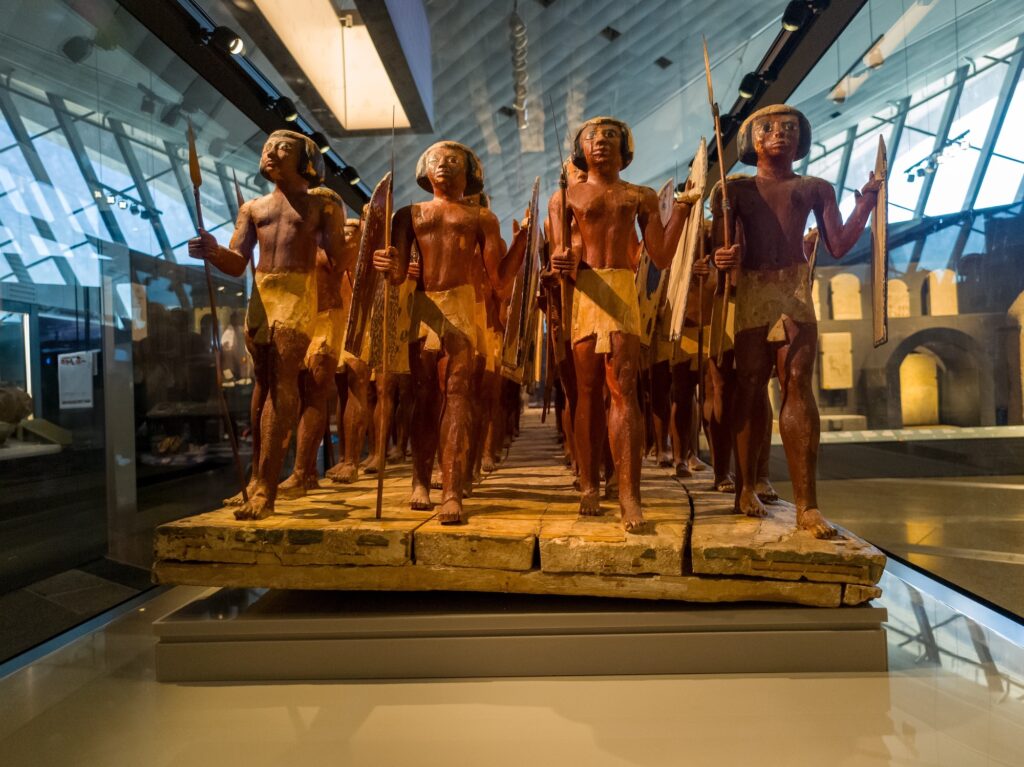 Wooden statues of ancient soldiers standing in a row at the Grand Egyptian Museum
