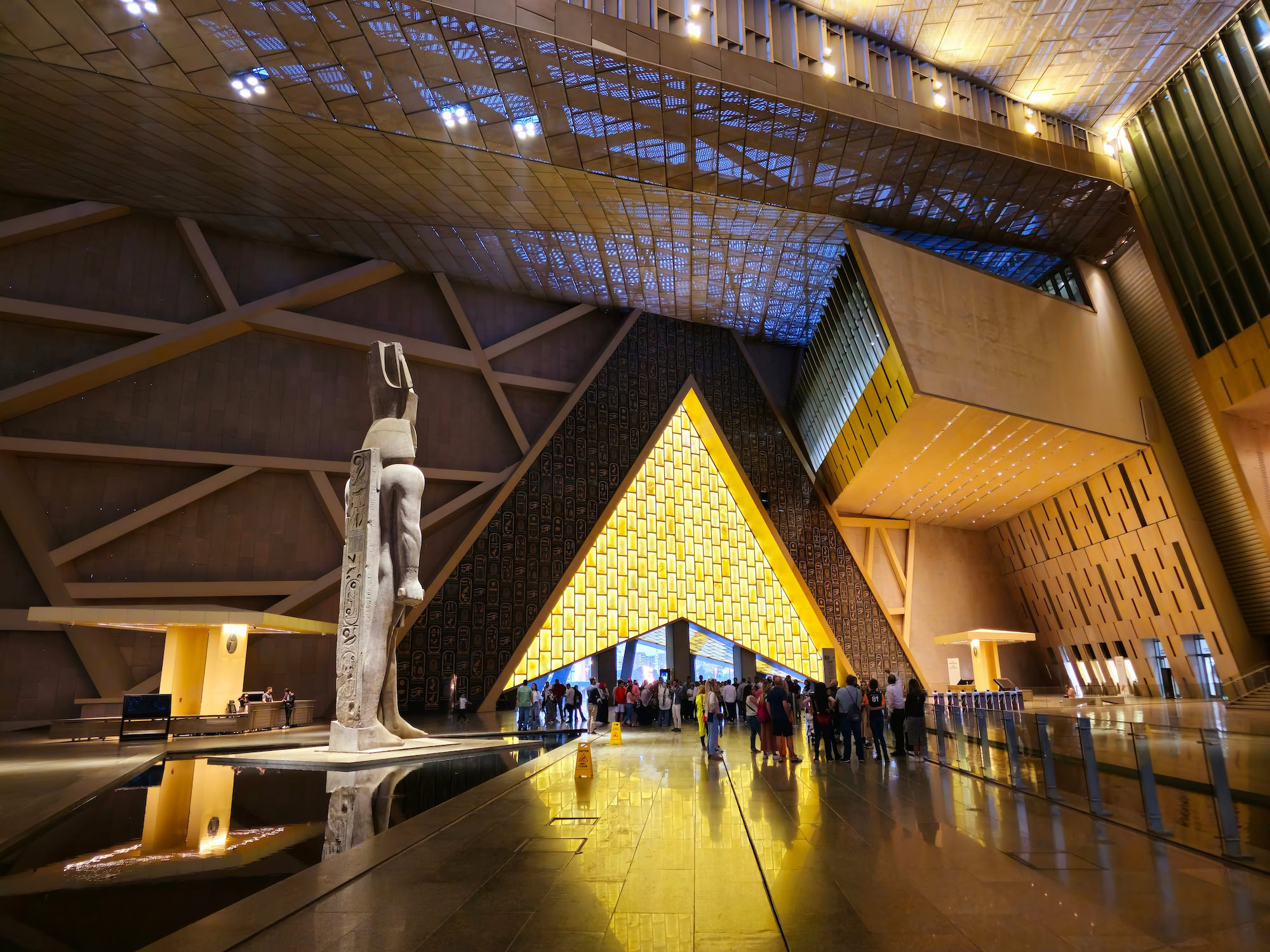 Luxurious Grand Egyptian Museum interior featuring golden ceiling, Egyptian statue, and elegant modern architecture