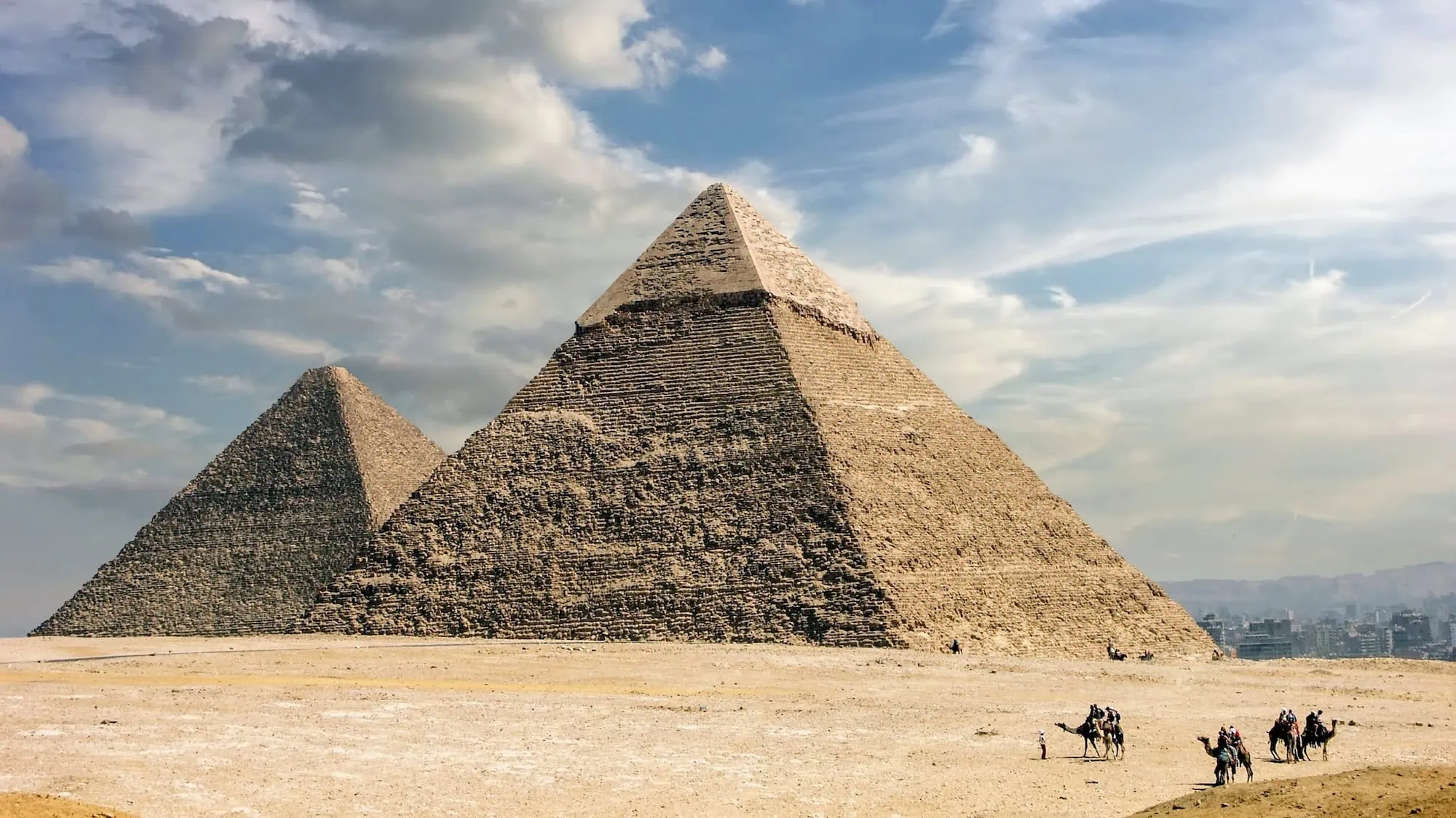 Great Pyramids of Giza with tourists and camels in desert landscape