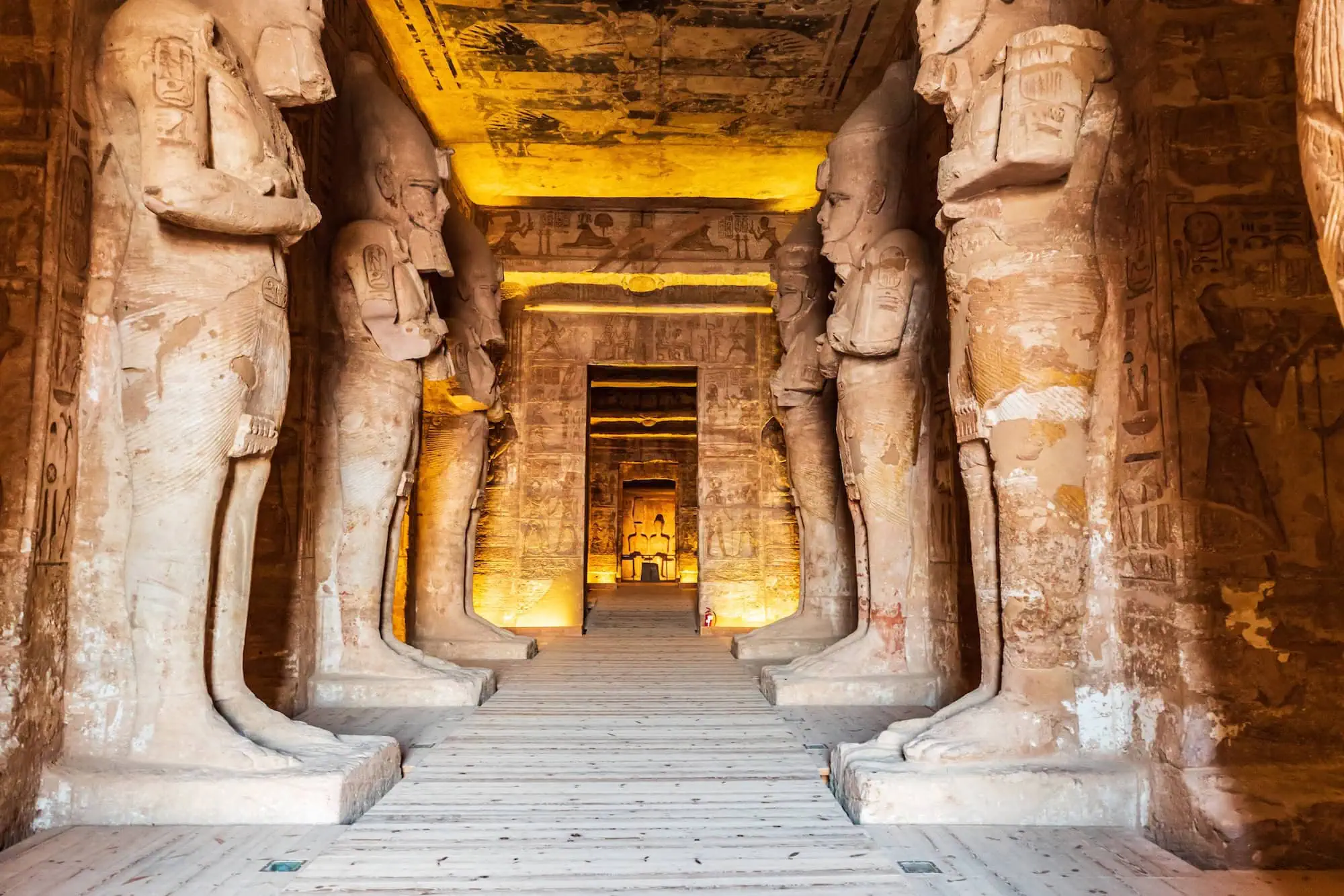 Ancient Egyptian temple interior showing carved columns, doorway, stairs, and hieroglyphic details