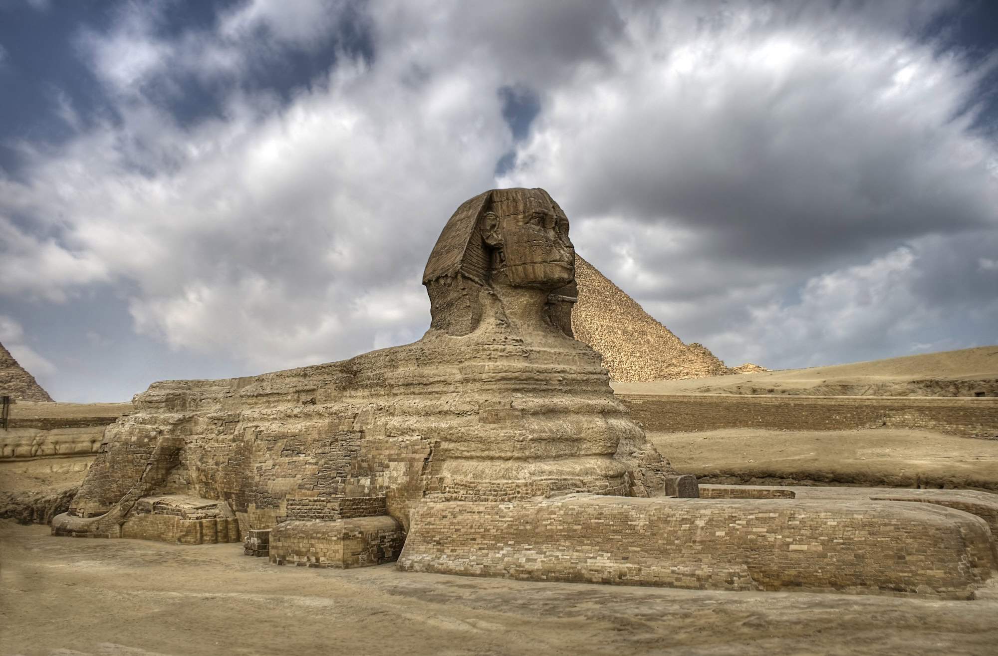 Grande Esfinge de Gizé com pirâmide ao fundo no deserto