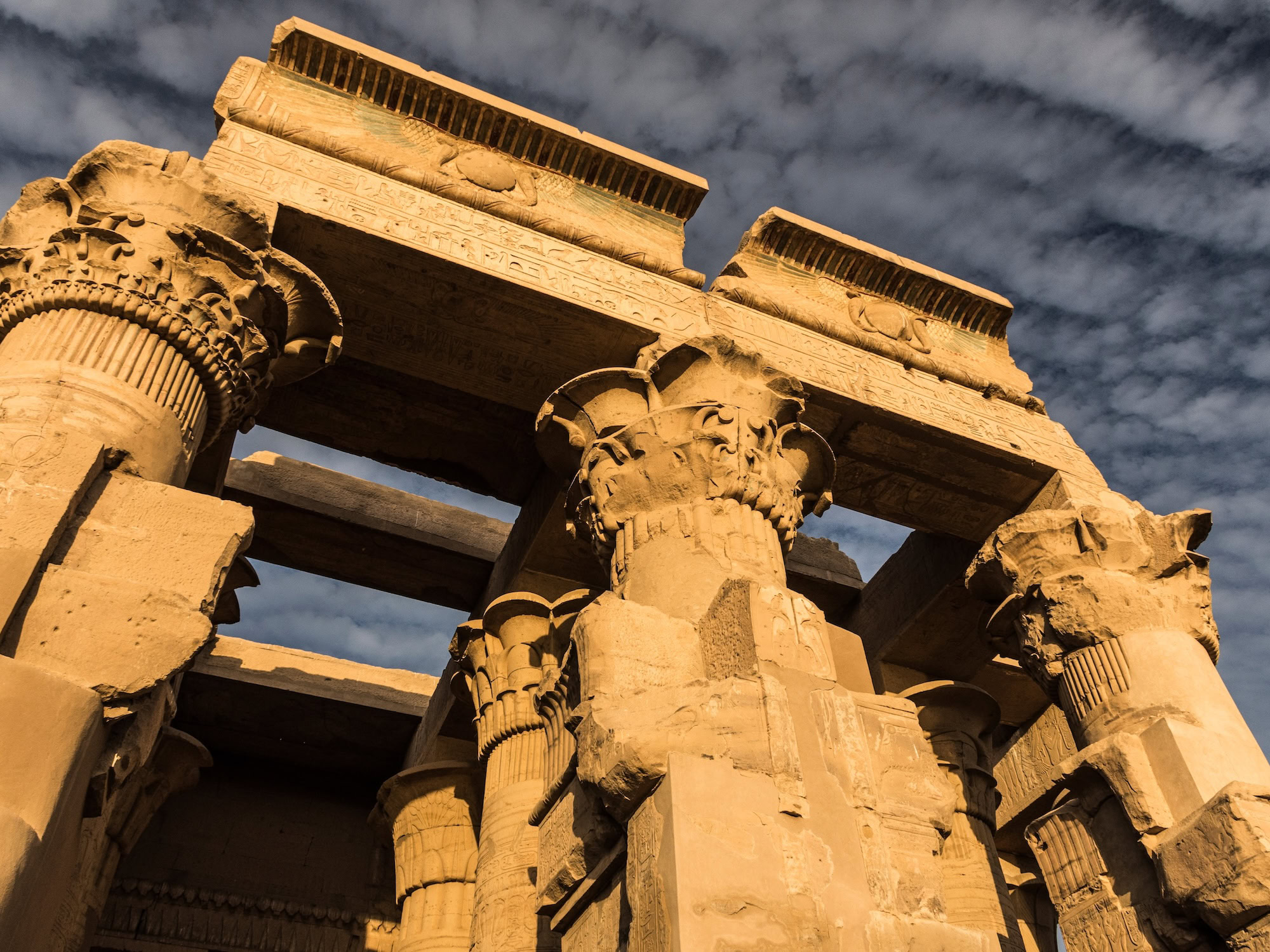 Ancient Kom Ombo Temple with towering carved columns, hieroglyphics, and dramatic sky in Egypt