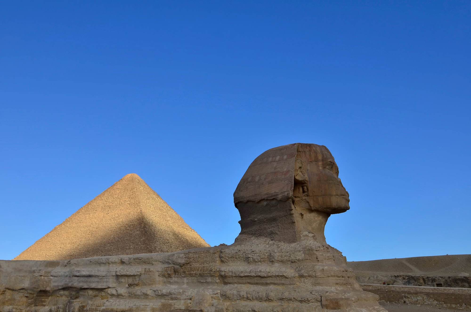 Great Sphinx and Great Pyramid of Giza against bright blue sky