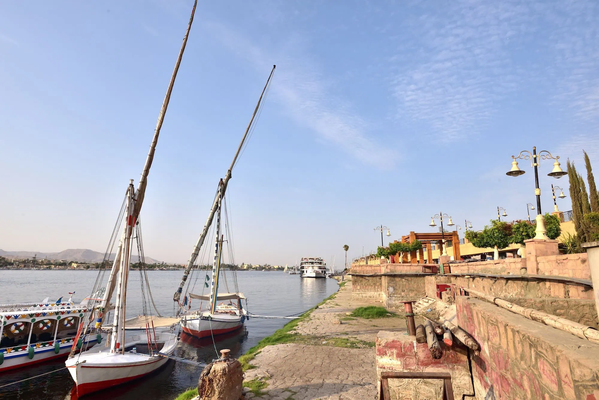 Barcos de cruzeiro e felucas tradicionais atracados no cais do Rio Nilo em Assuã