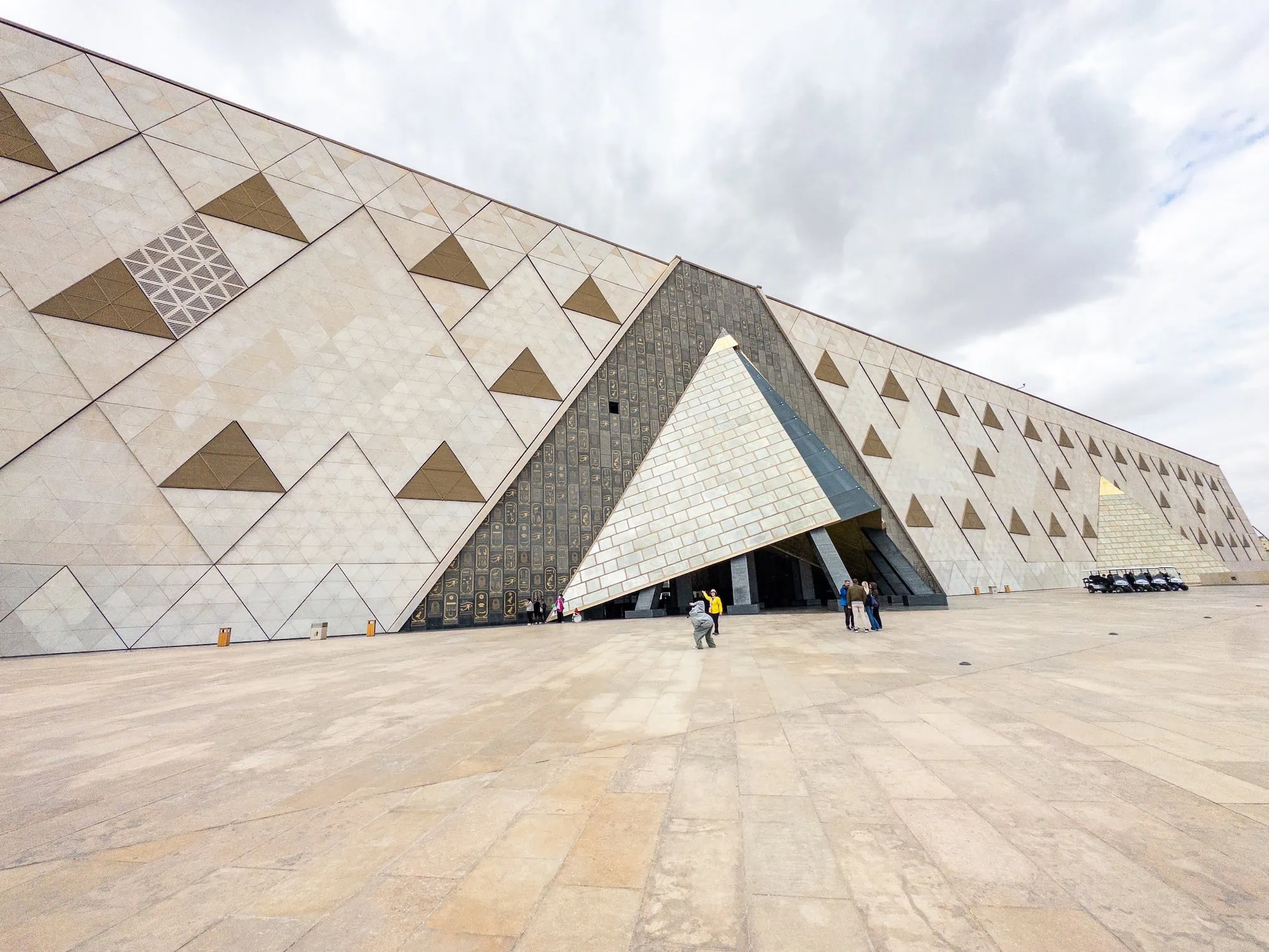 Grand Egyptian Museum exterior with triangular geometric facade and visitors