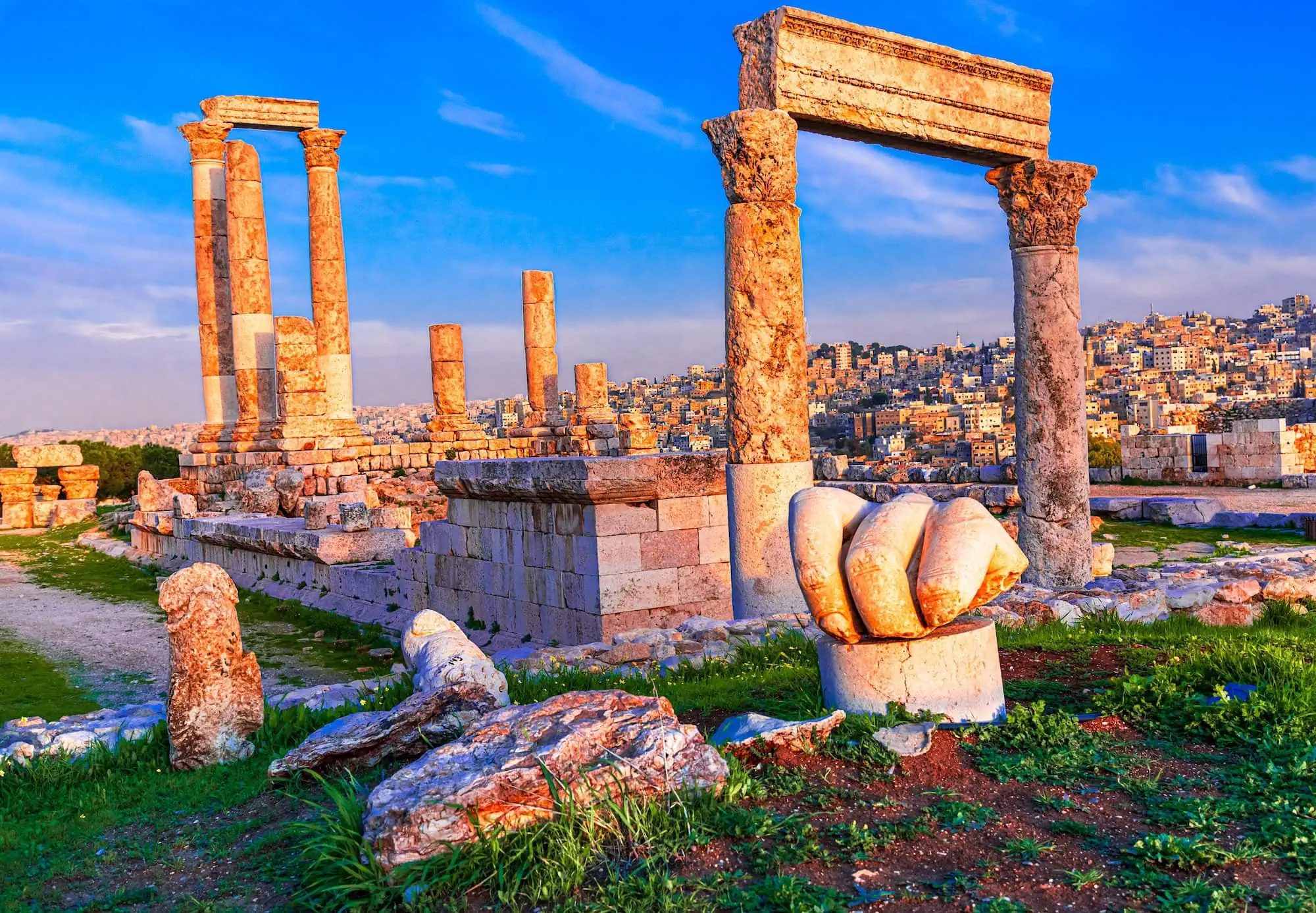 Ancient Temple of Hercules ruins with stone columns and carved hand sculpture at Amman Citadel during sunset