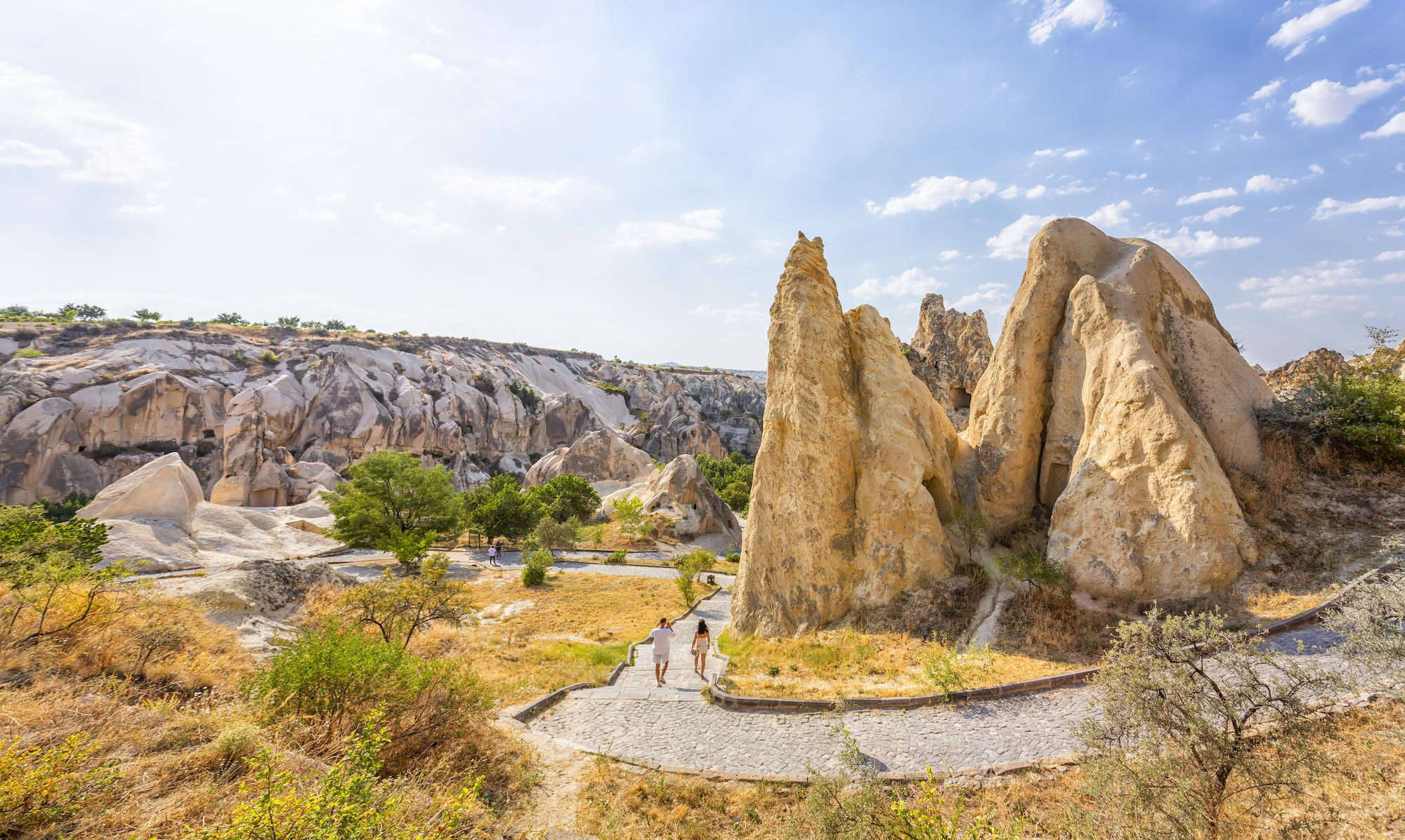 Tourists walking on stone paths through fairy chimney rock formations in Cappadocia