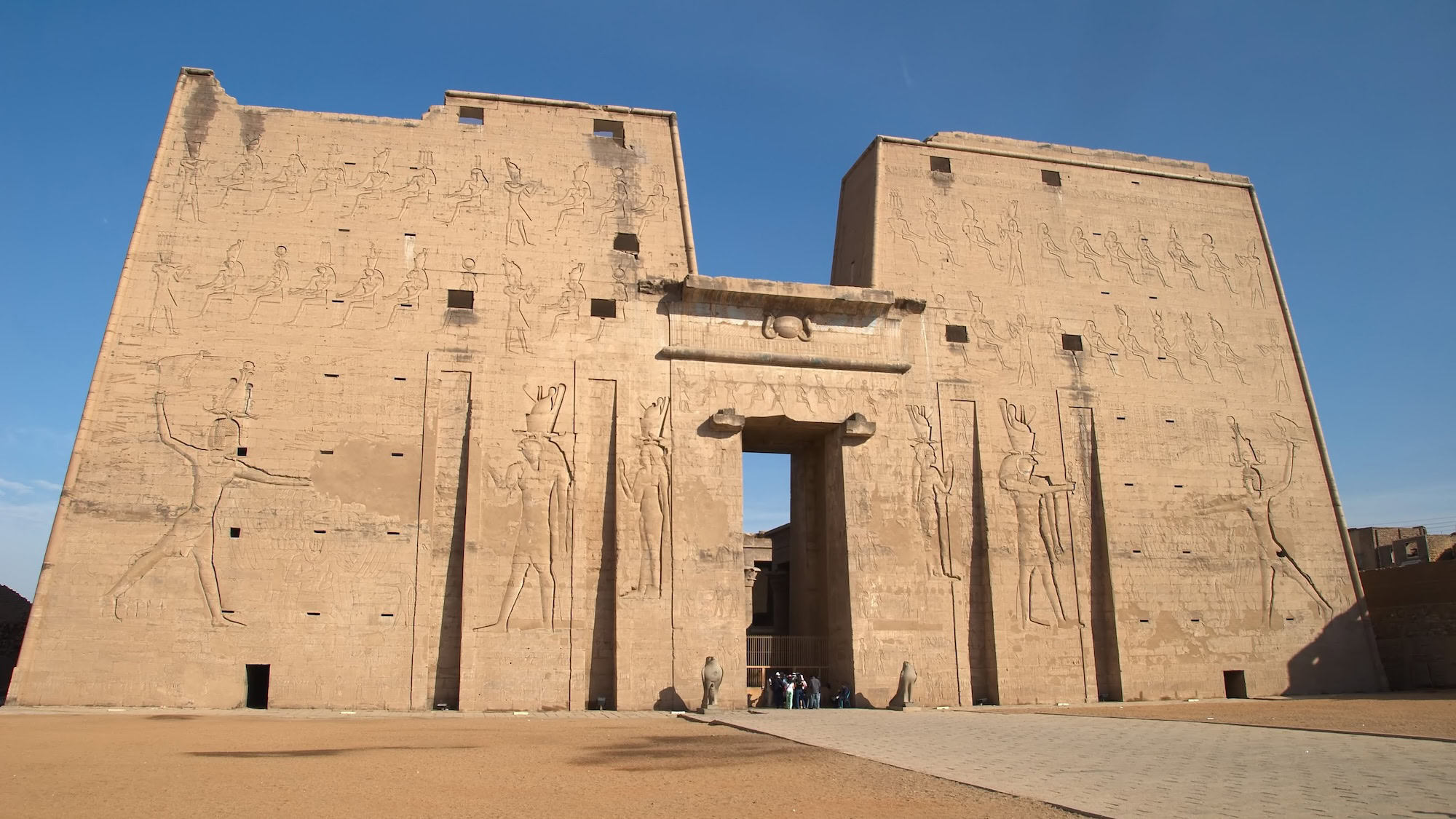 Entrada do Templo de Edfu com pilones massivos e hieróglifos gravados nas paredes de arenito