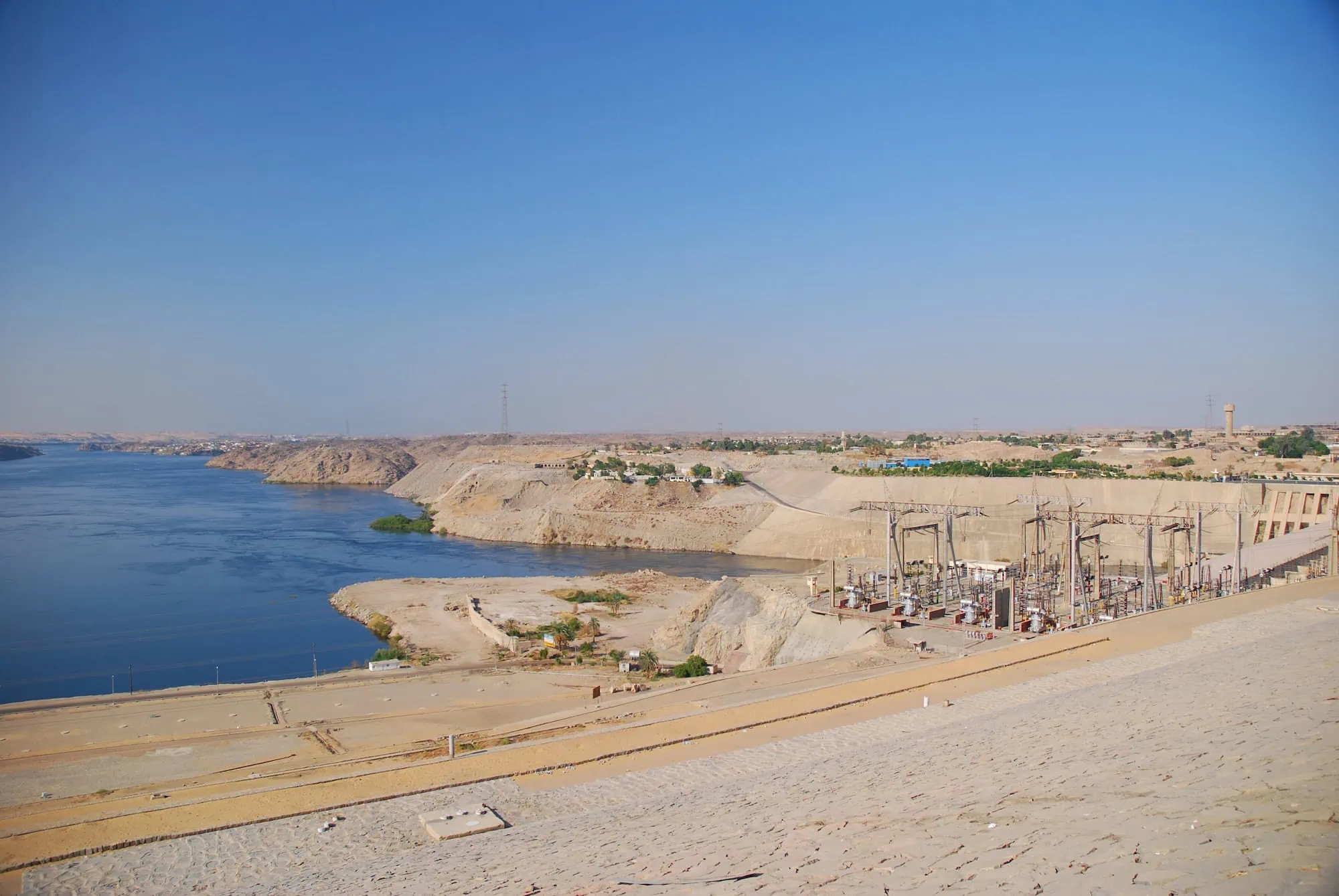 Aswan High Dam with reservoir and construction equipment in desert landscape