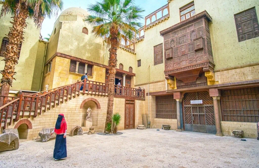 A courtyard view with arched colonnades, stone paving, and historic architectural details inside the Coptic Museum complex, Cairo