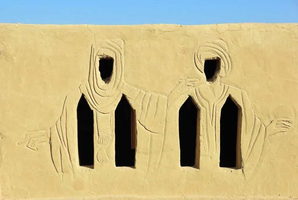 Plastered wall and windows shaped as figures of two people in traditional Arab clothing on the facade of the Museum of Badr, Badr