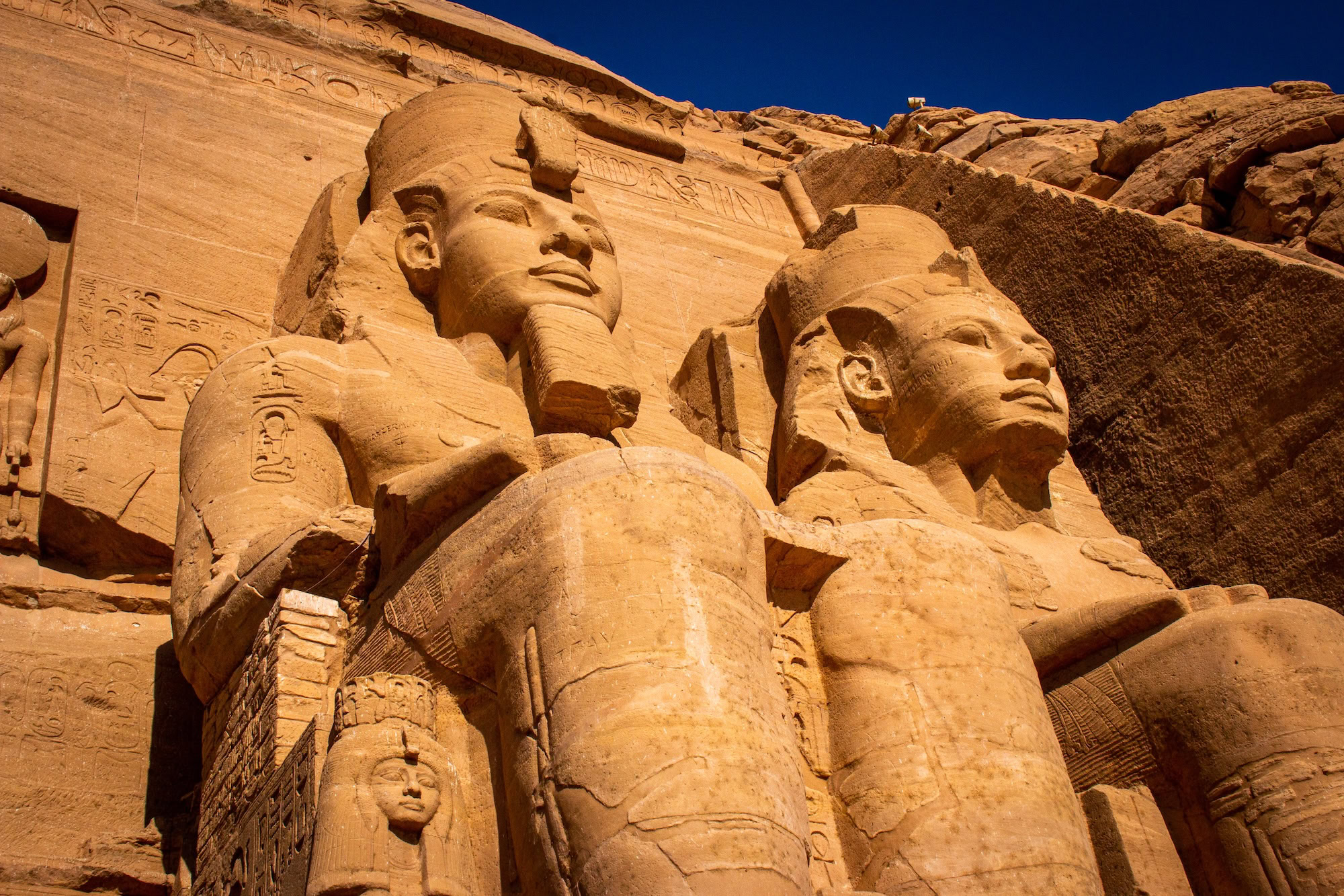 Abu Simbel temple facade with colossal statues of Pharaoh Ramses II and hieroglyphics
