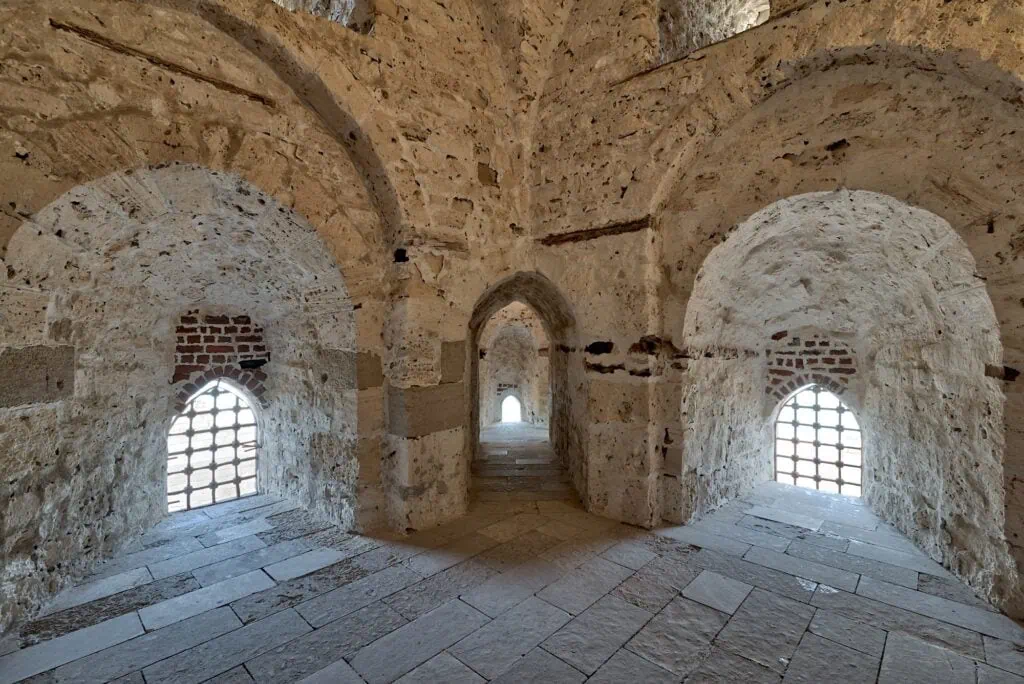 Three stone arches opening to window views along a brick passageway surrounding the Citadel of Qaitbay, Alexandria