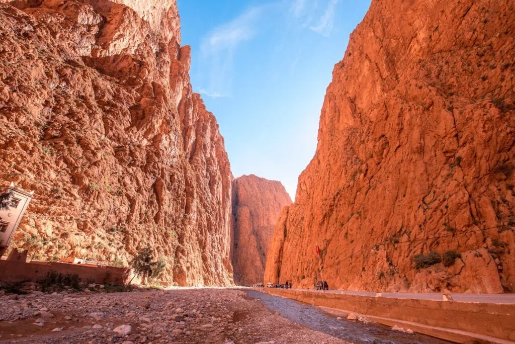 Todgha Gorge with tall limestone canyon walls rising above a narrow riverbed and a path running through the valley, Tinerhir