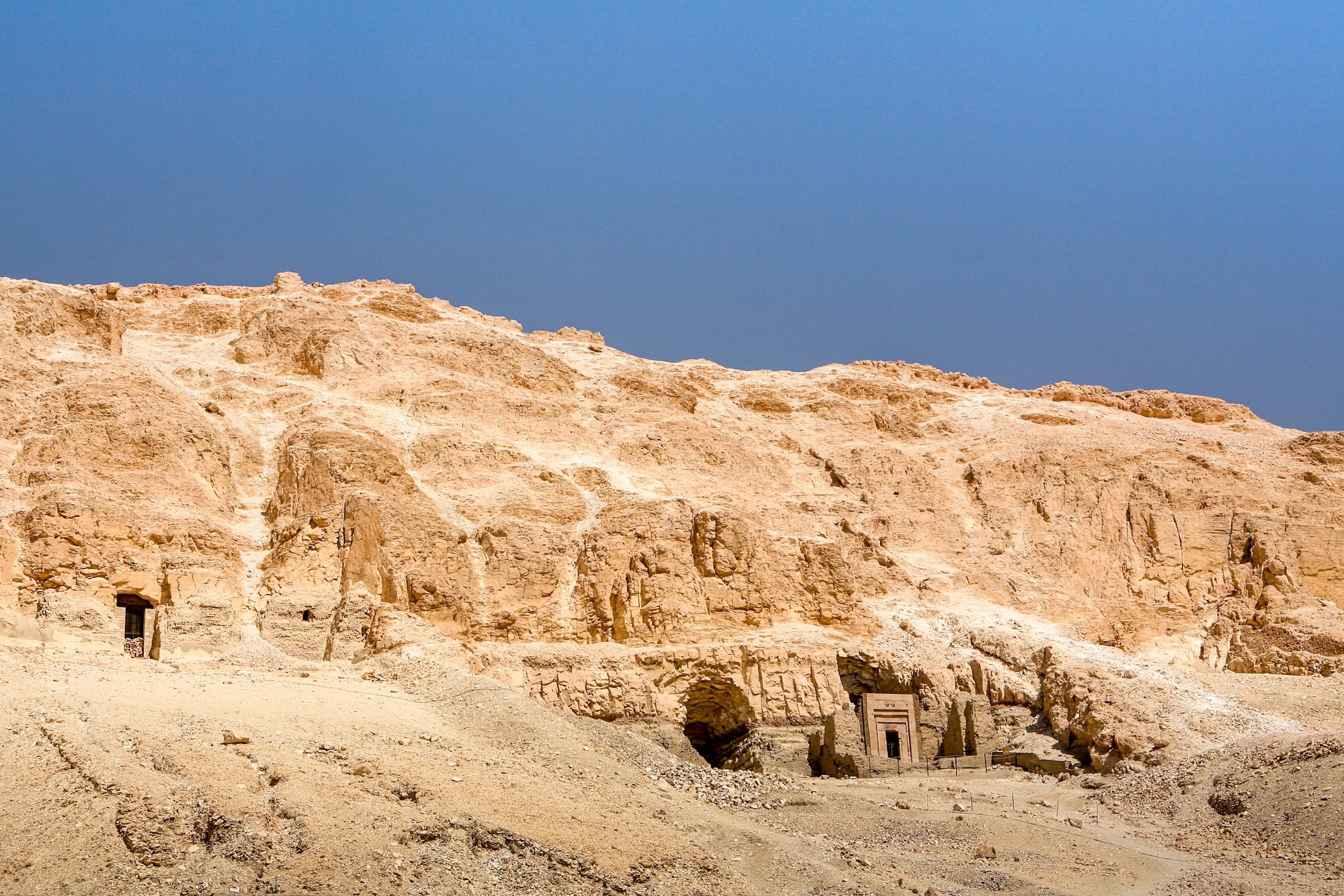 Ancient tomb entrances carved into limestone cliffs in Valley of Kings necropolis