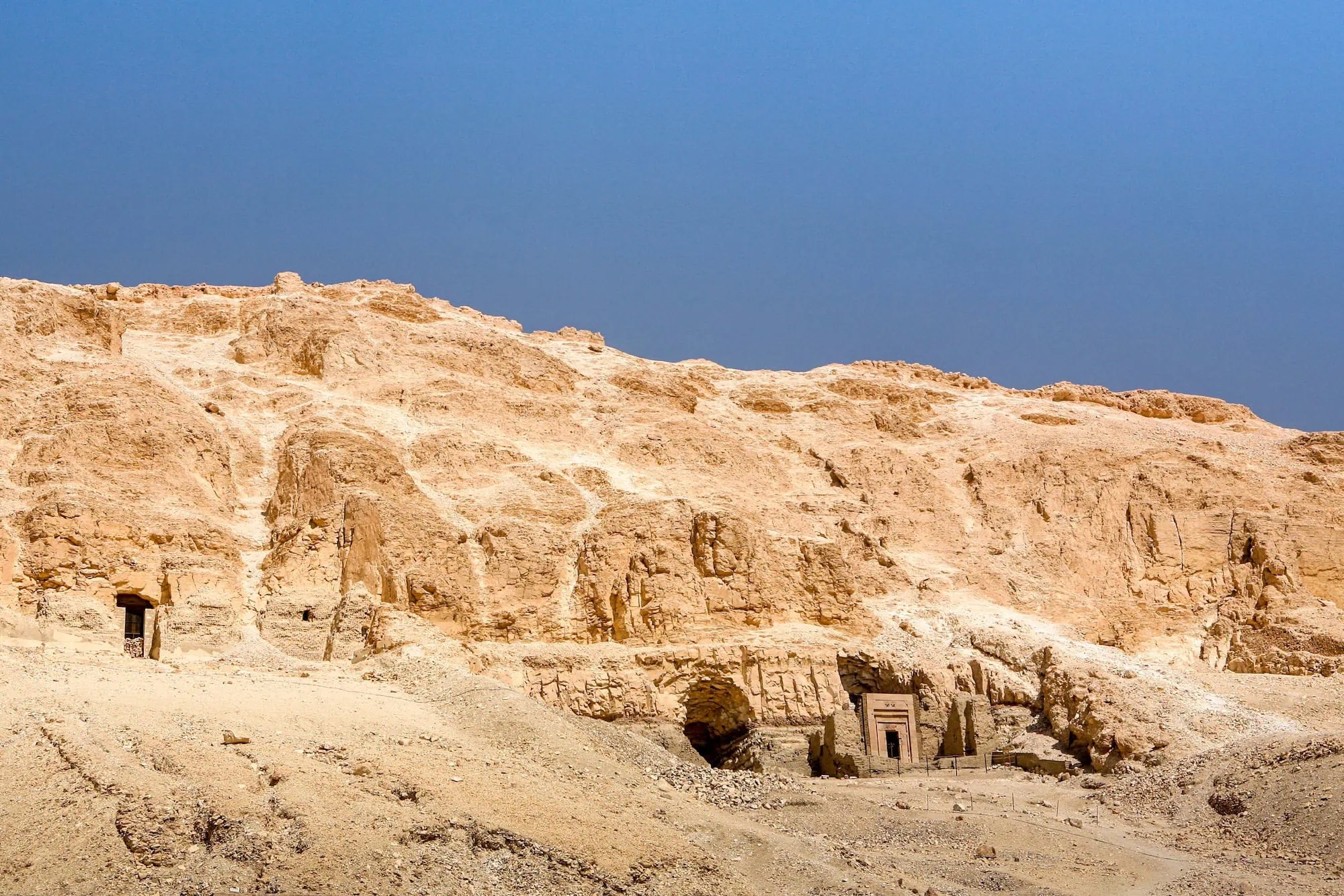 Ancient tomb entrances carved into limestone cliffs in Valley of the Kings