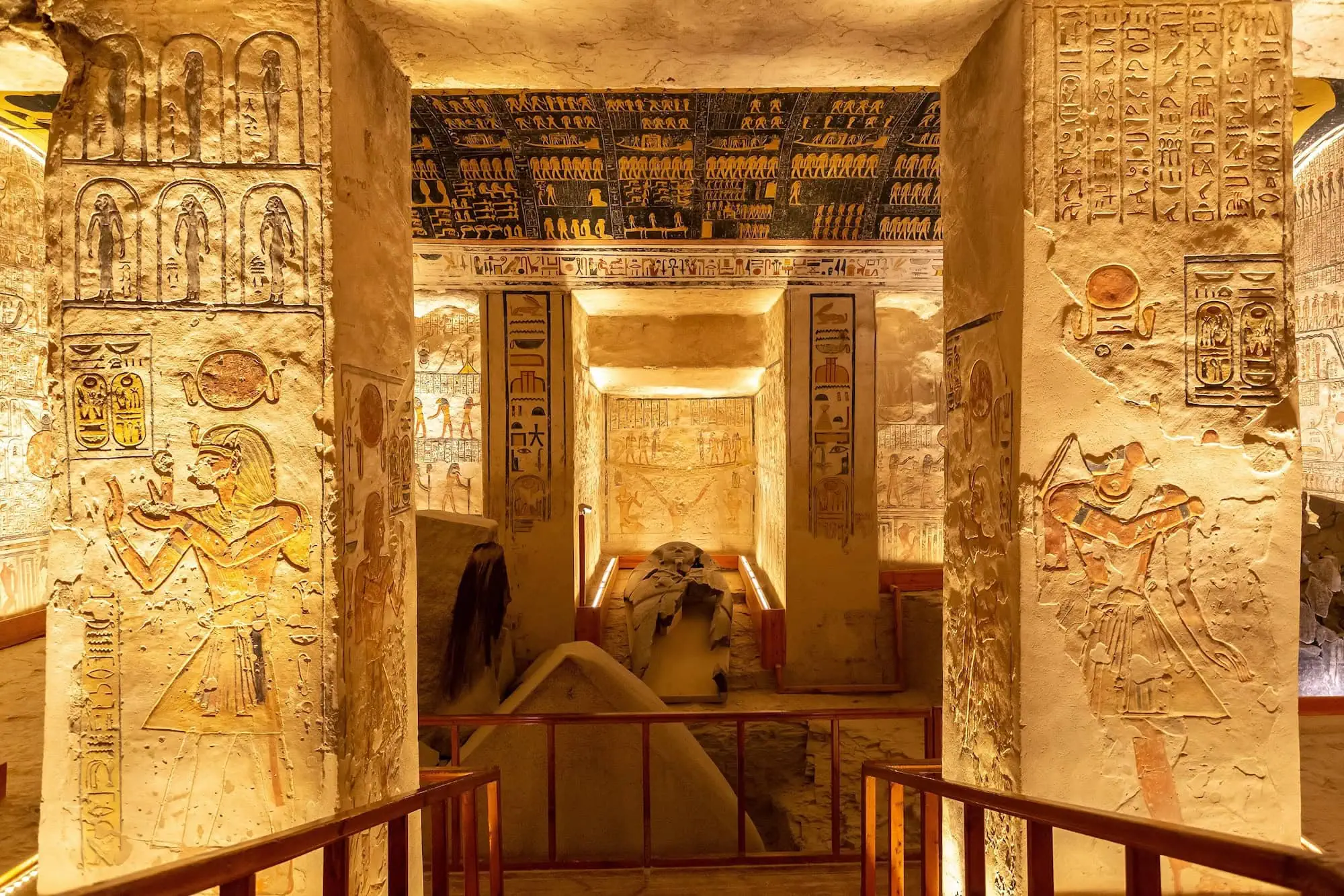 Ornate tomb interior with golden wall paintings and hieroglyphics at Valley of the Kings