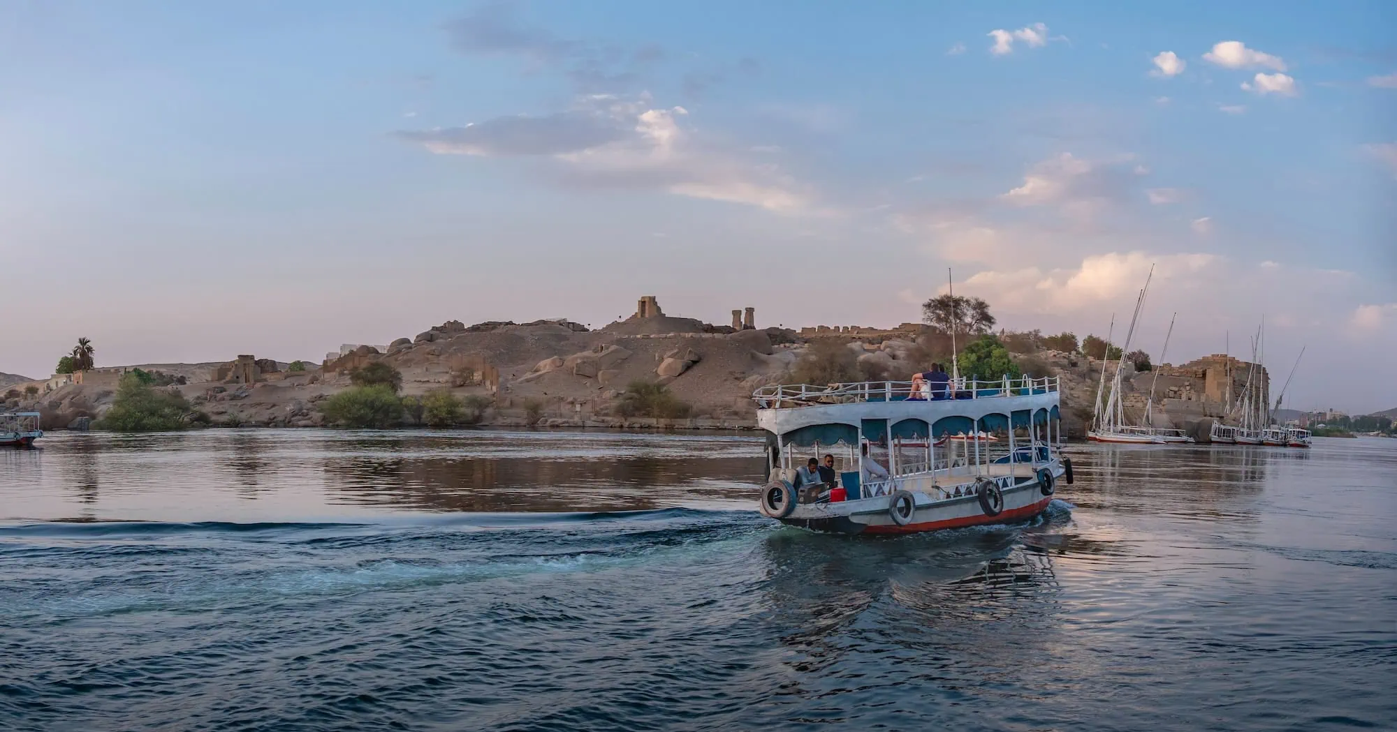 Boats on the Nile River near Elephantine Island in Aswan with ancient ruins and desert landscape