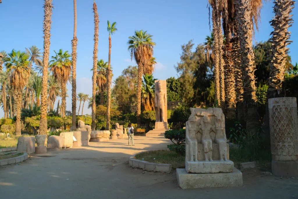 Tourists standing near a colossal limestone statue of King Ramses II displayed at the Mit Rahina open-air museum, Memphis