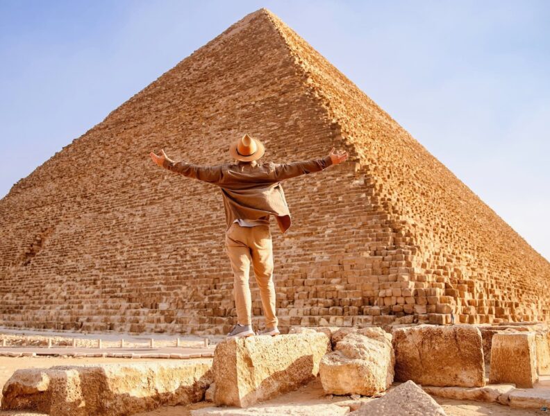 5-Day Tour of Cairo. A man standing on a rock at the pyramids with his arms out in the air
