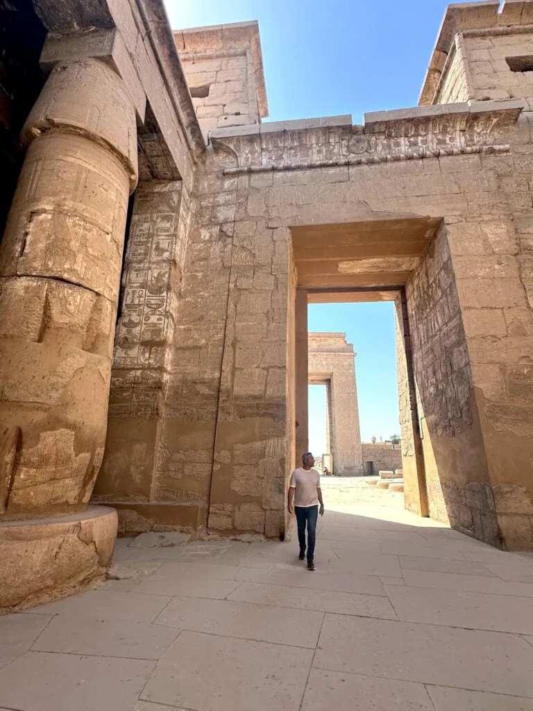 Visitor walking among decorated stone columns and wall reliefs inside the Temple of Khonsu at Karnak Temple, Luxor