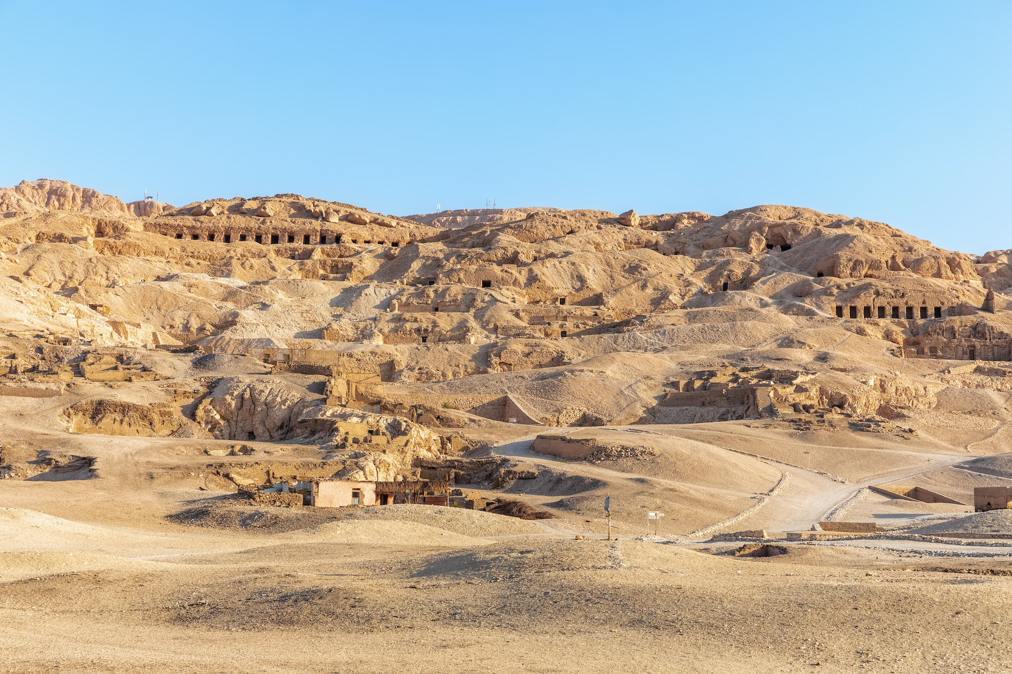 Ancient tomb entrances carved into limestone cliffs in Valley of the Kings